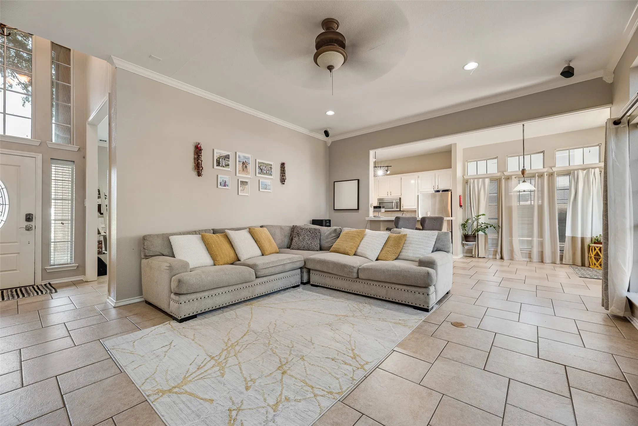 Spacious living area featuring tile flooring, a ceiling fan, recessed lighting, and a sightline to the kitchen