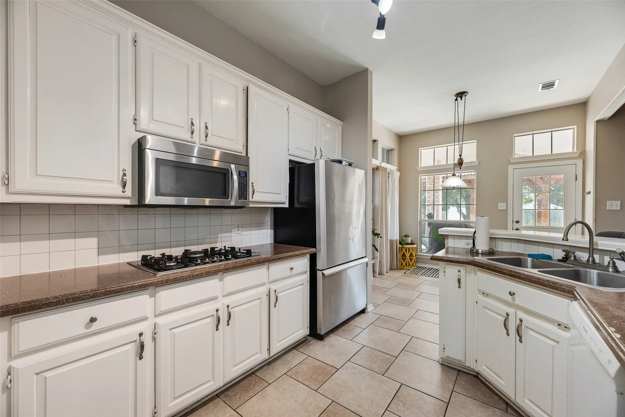 Kitchen featuring white cabinetry, stainless steel appliances, a gas cooktop, tile flooring, and a double basin sink