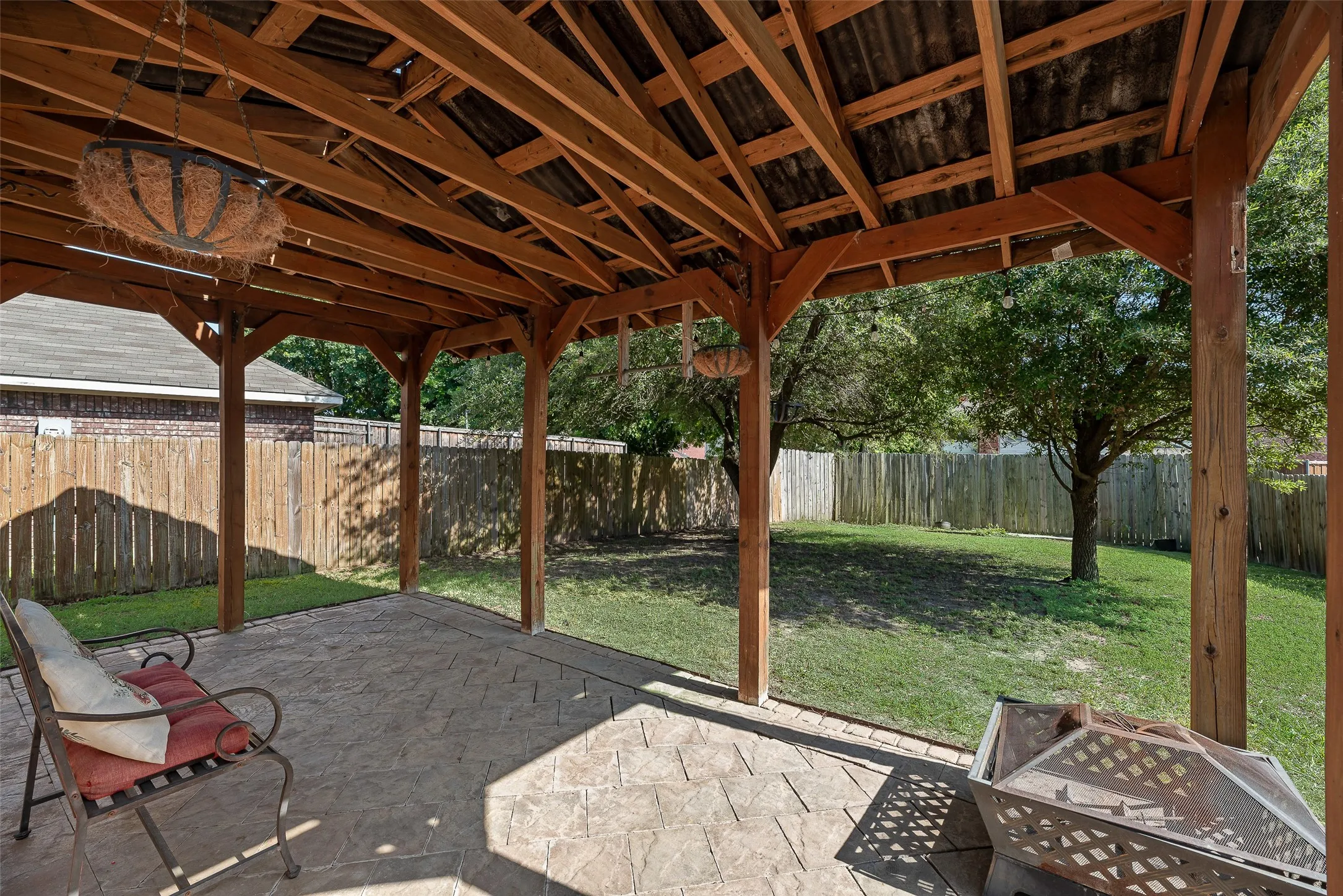 Expansive covered patio with stamped concrete flooring and a natural wood beam ceiling