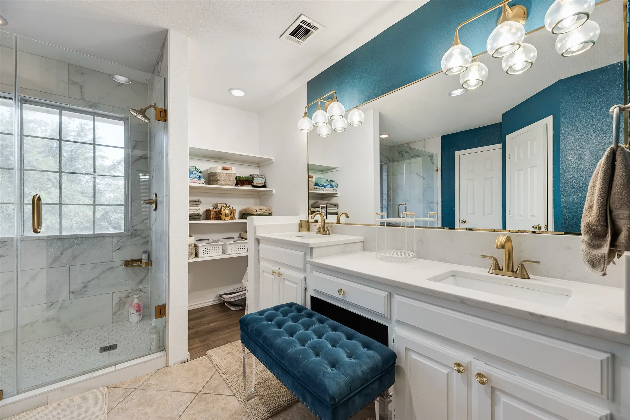 Bathroom featuring a dual vanity with undermount sinks, gold-finish fixtures, and a large mirror