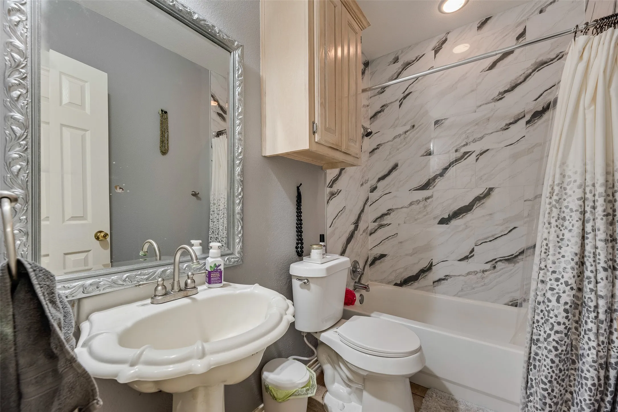 Bathroom featuring a pedestal sink, white toilet, and a white bathtub with a tile surround