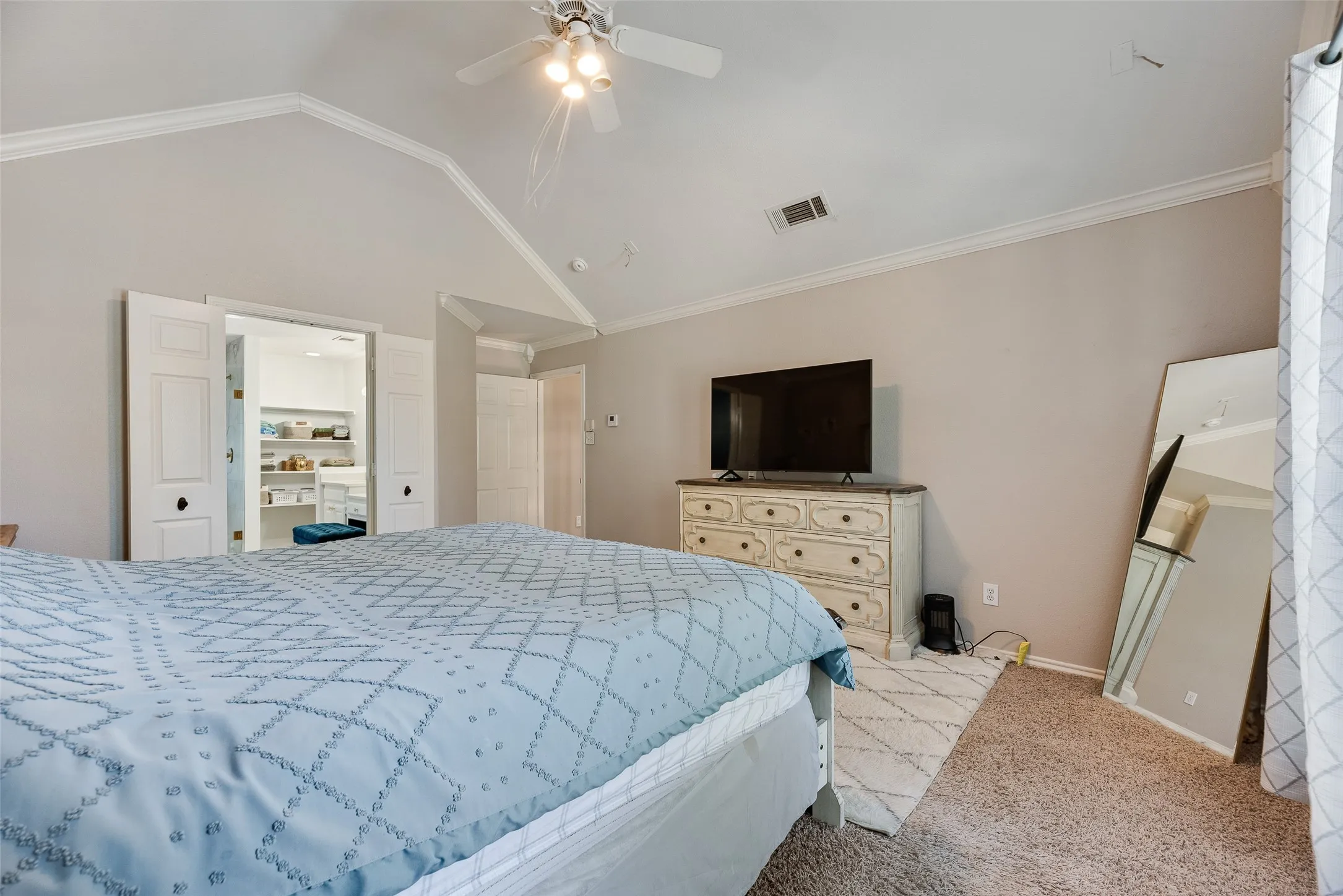 Vaulted ceiling with crown molding, ceiling fan, and carpeted flooring
