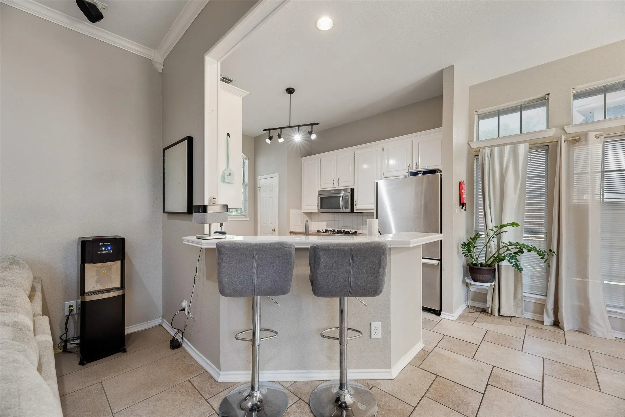 Kitchen featuring a peninsula breakfast bar, white cabinetry, stainless steel appliances, and track lighting