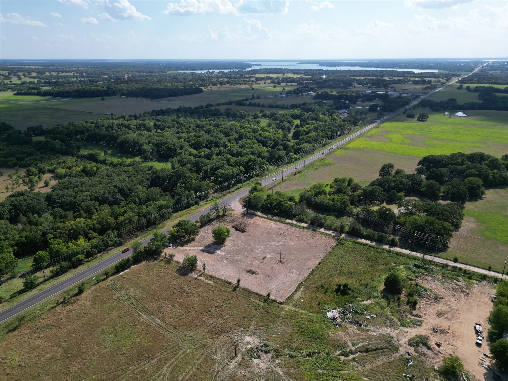 Expansive aerial perspective showcasing a cleared land parcel alongside a paved roadway