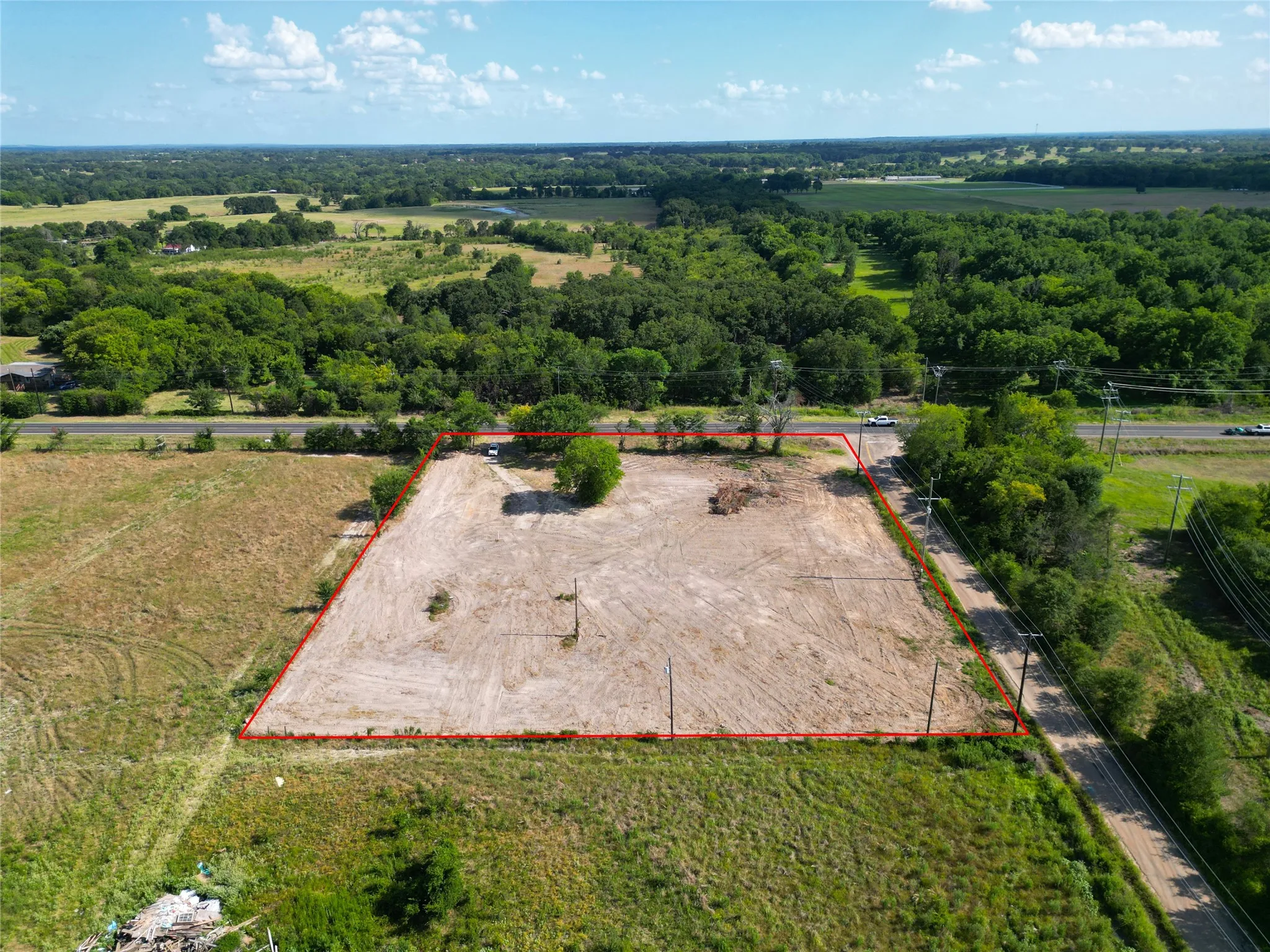 Expansive land parcel with visible boundary lines, featuring a partially cleared lot