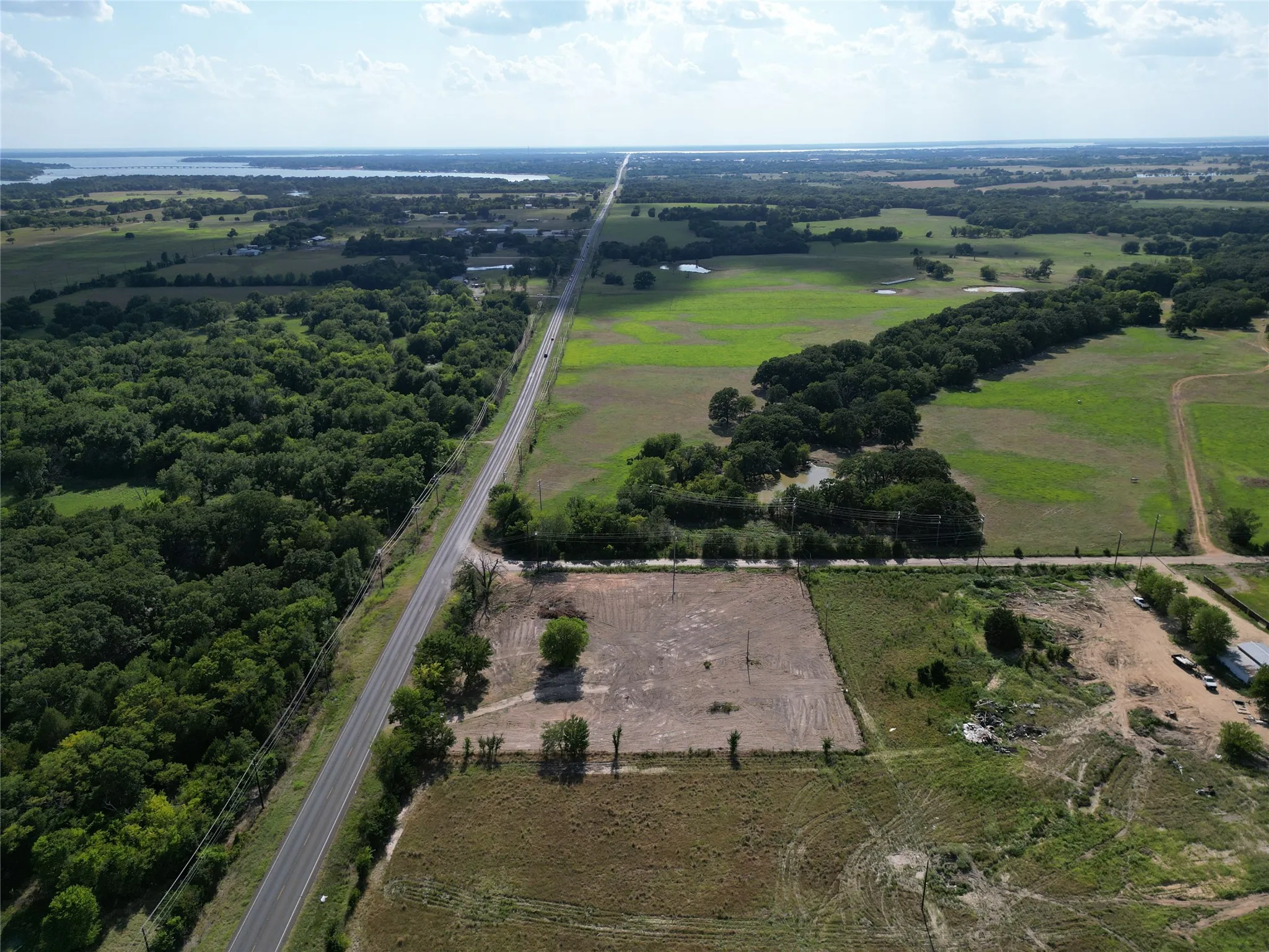 Expansive rural property featuring an established roadway, numerous trees, and open land