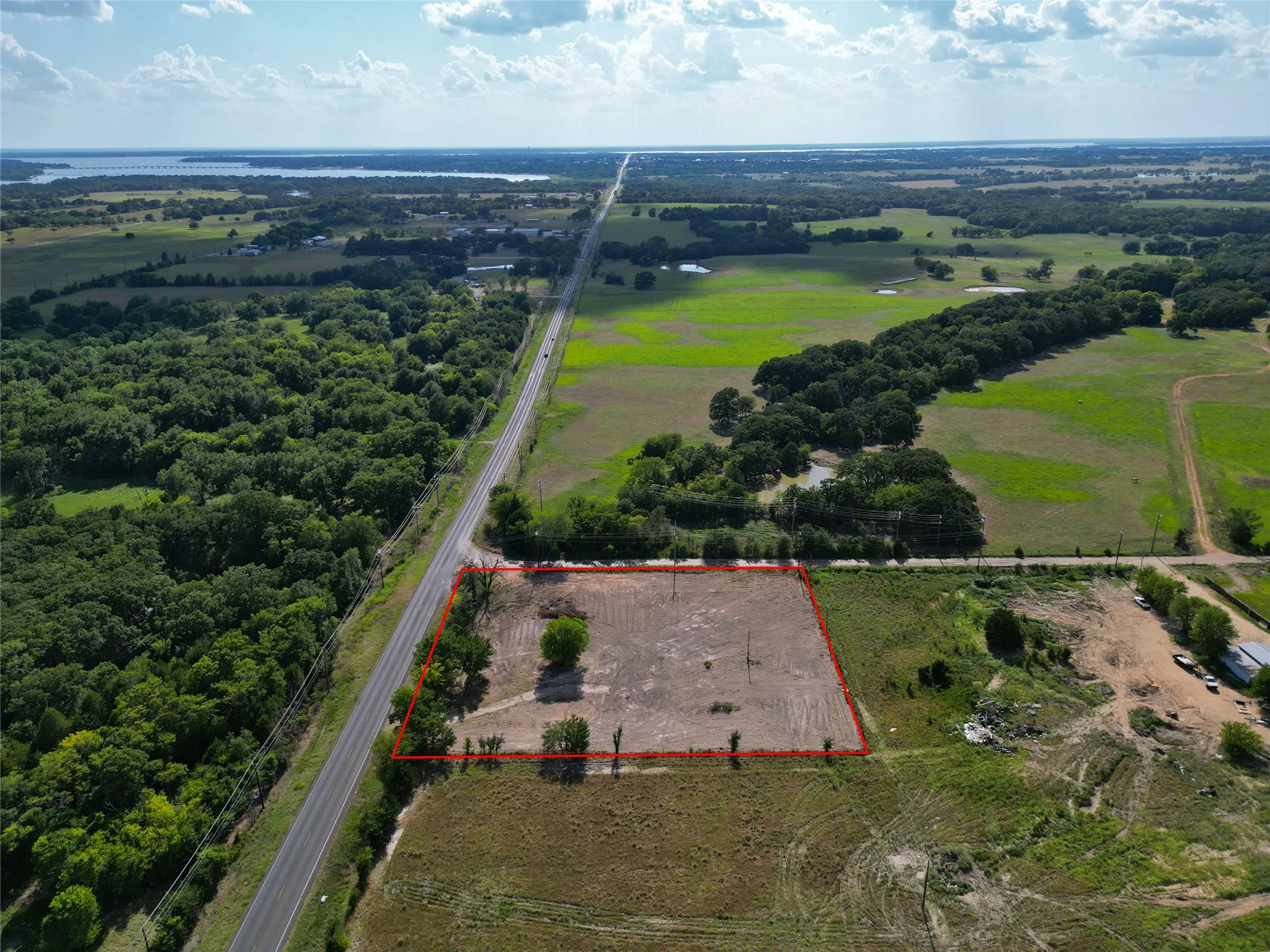 Cleared land parcel featuring established tree lines and direct road frontage