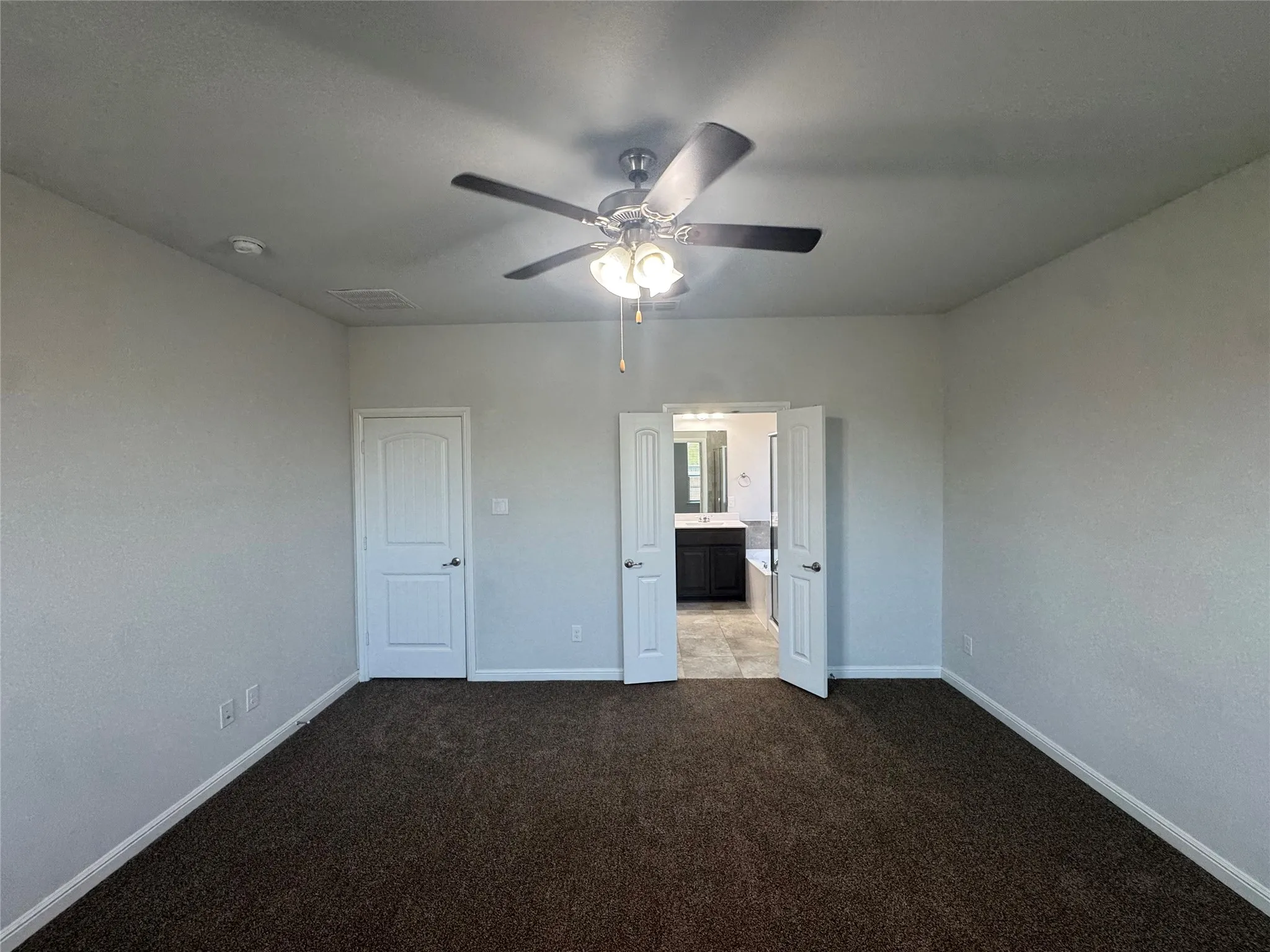 Textured wall finish, ceiling fan with integrated lighting, paneled interior doors, and carpet flooring