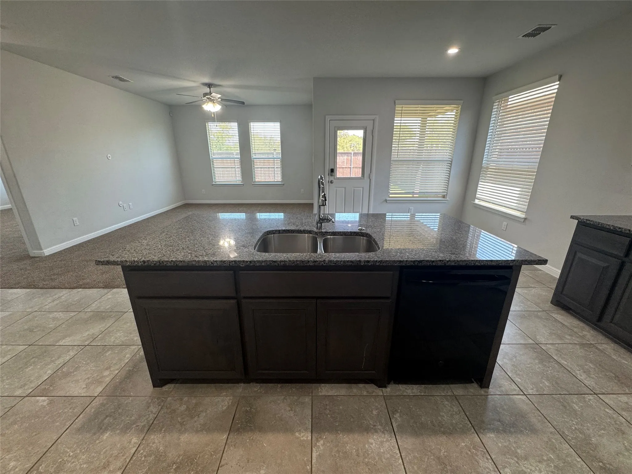 Kitchen island with granite countertop, double stainless steel sink, and integrated dishwasher
