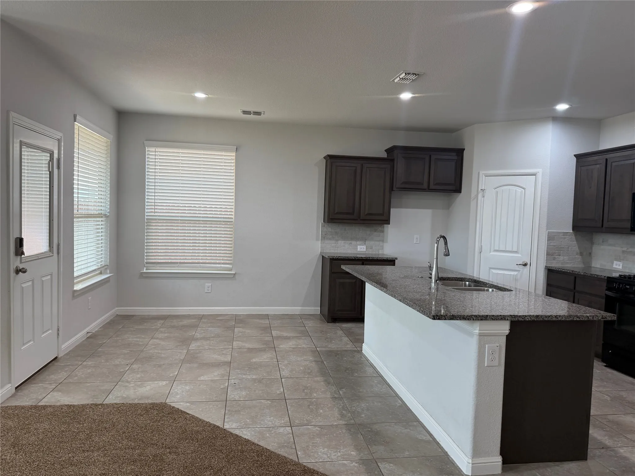 Open-concept kitchen and dining area featuring a central island with a double basin sink and gooseneck faucet