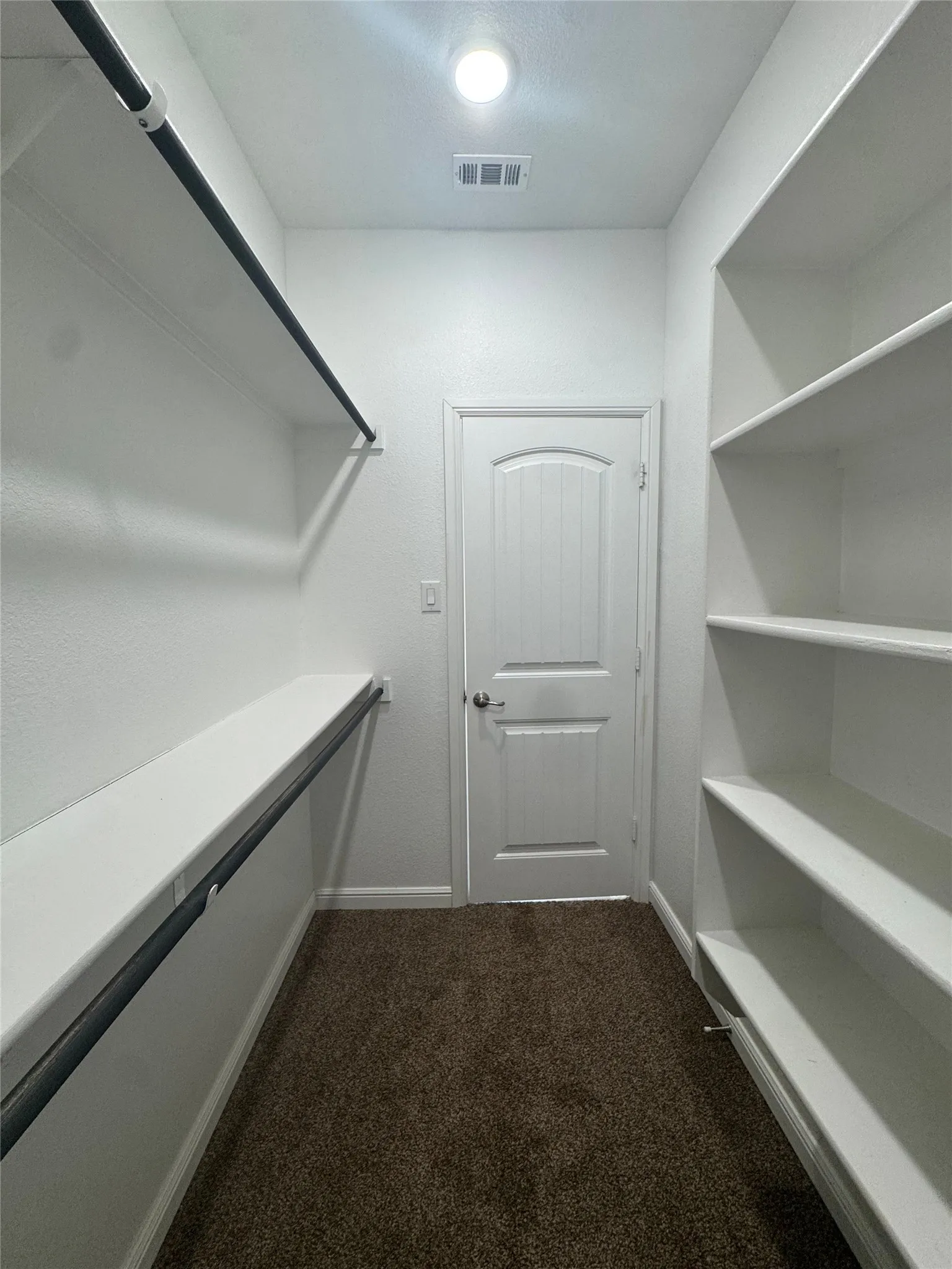 Spacious closet featuring built-in shelving, a hanging rod, and recessed lighting