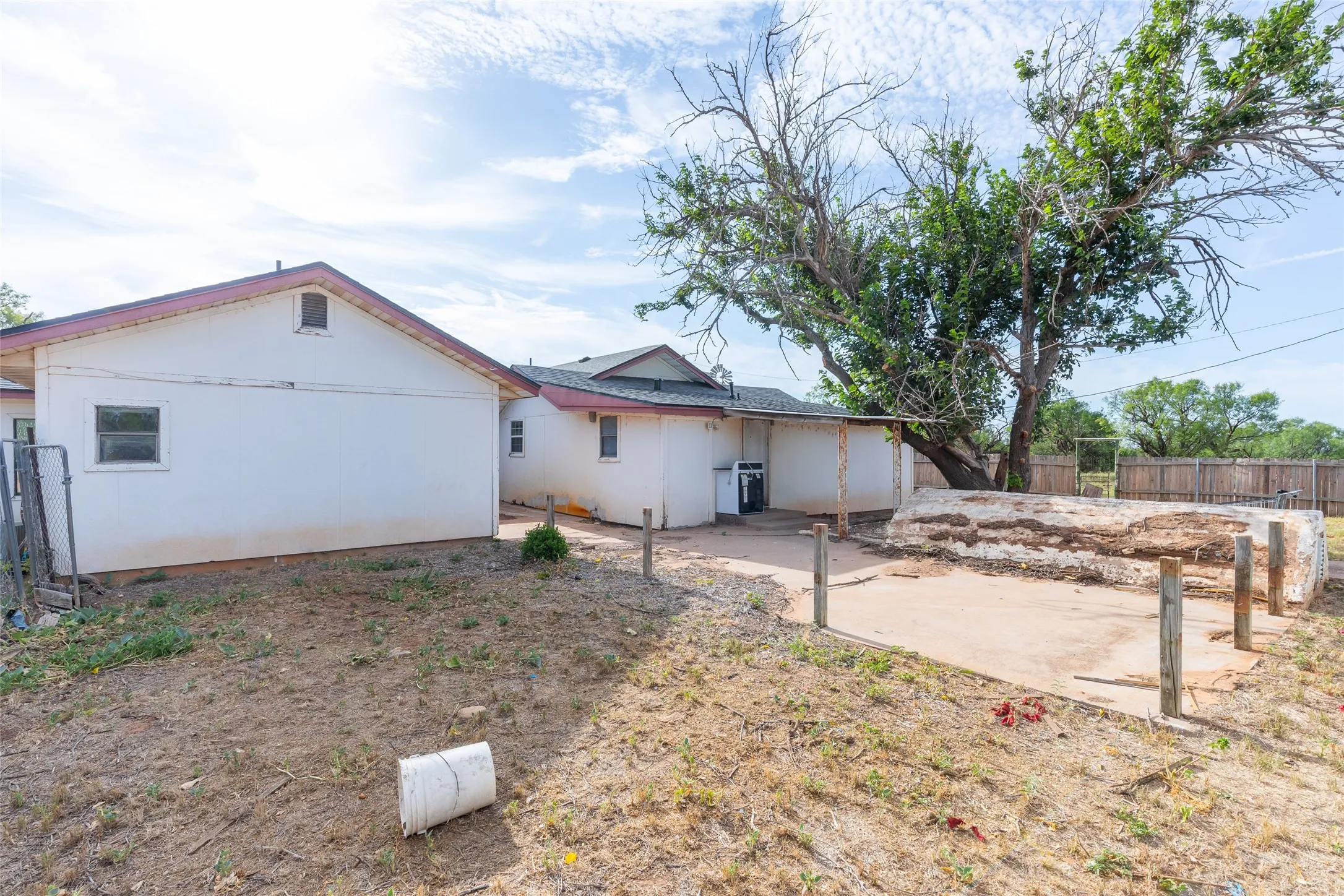 Rear exterior featuring a large mature tree, a concrete patio area, and a covered back porch