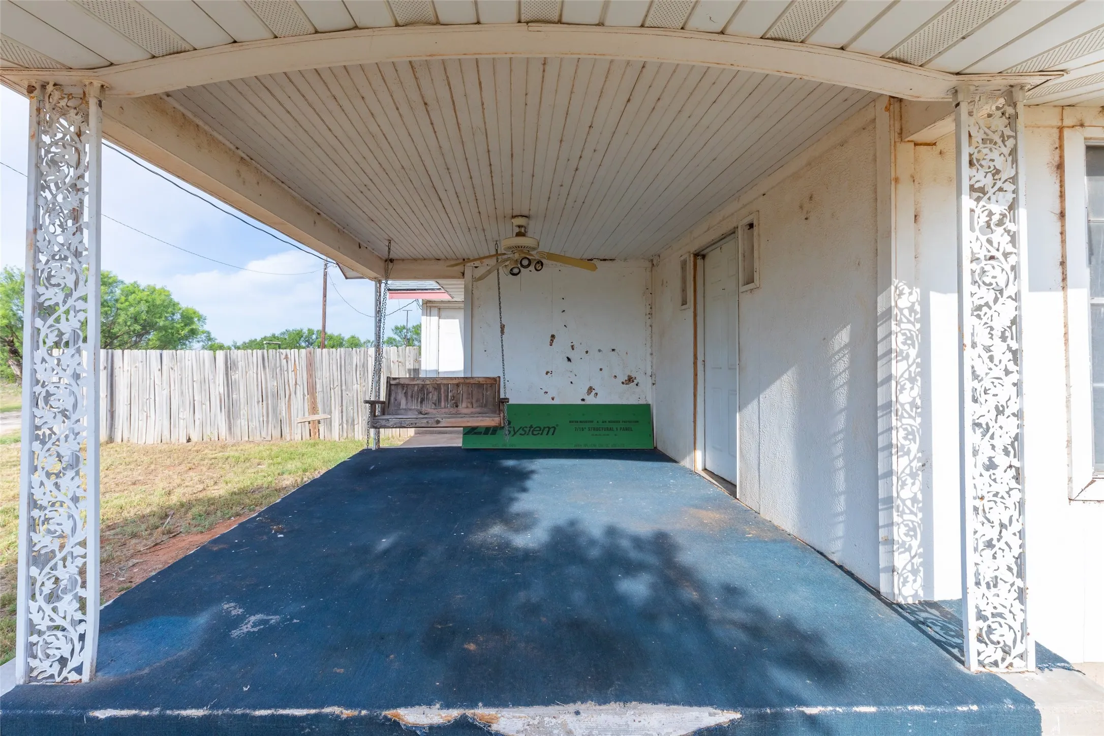Covered front porch featuring decorative metal support columns and a ceiling fan