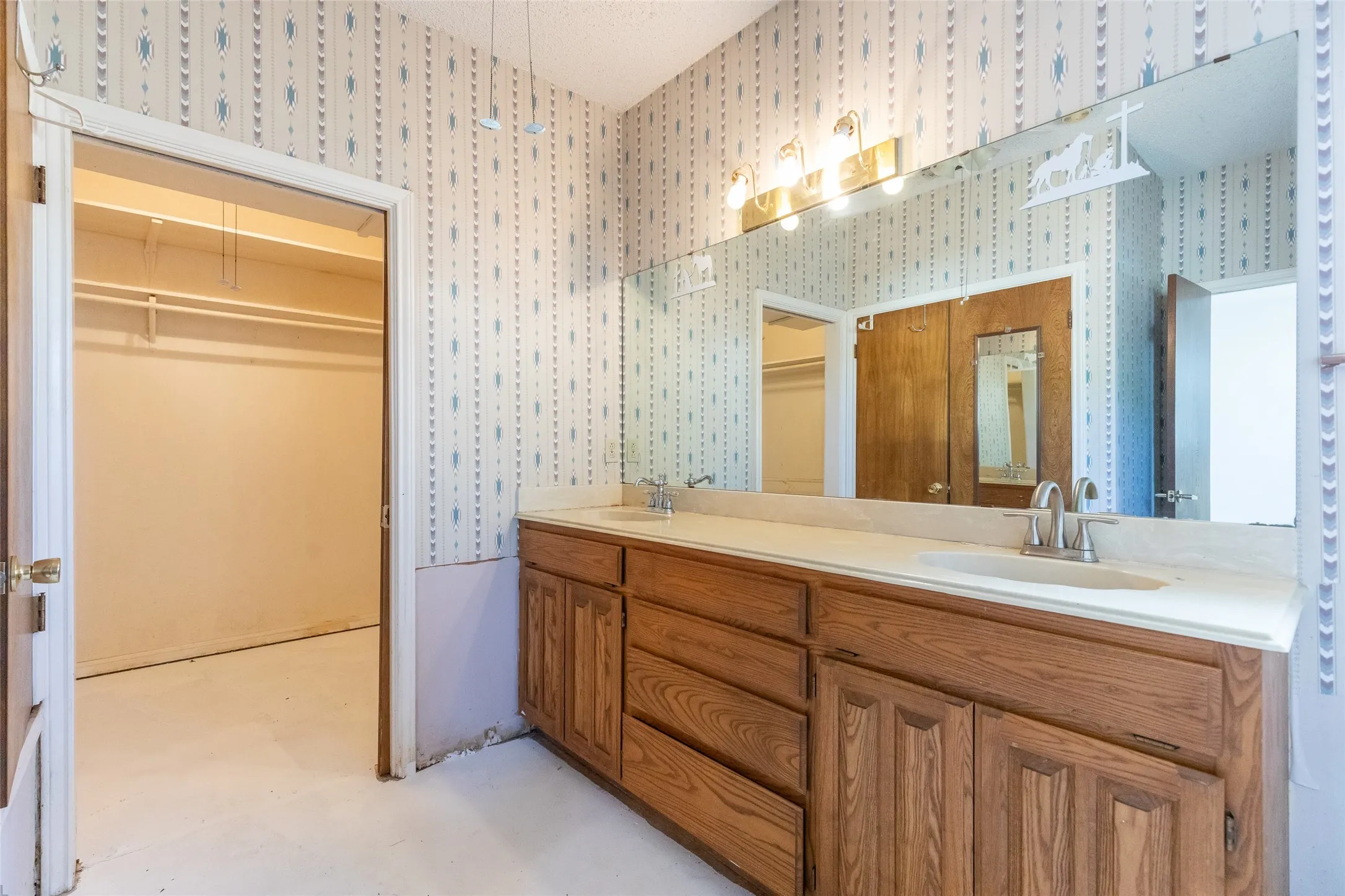 Bathroom featuring a double vanity with wood cabinetry, integrated sinks, and a large wall-mounted mirror
