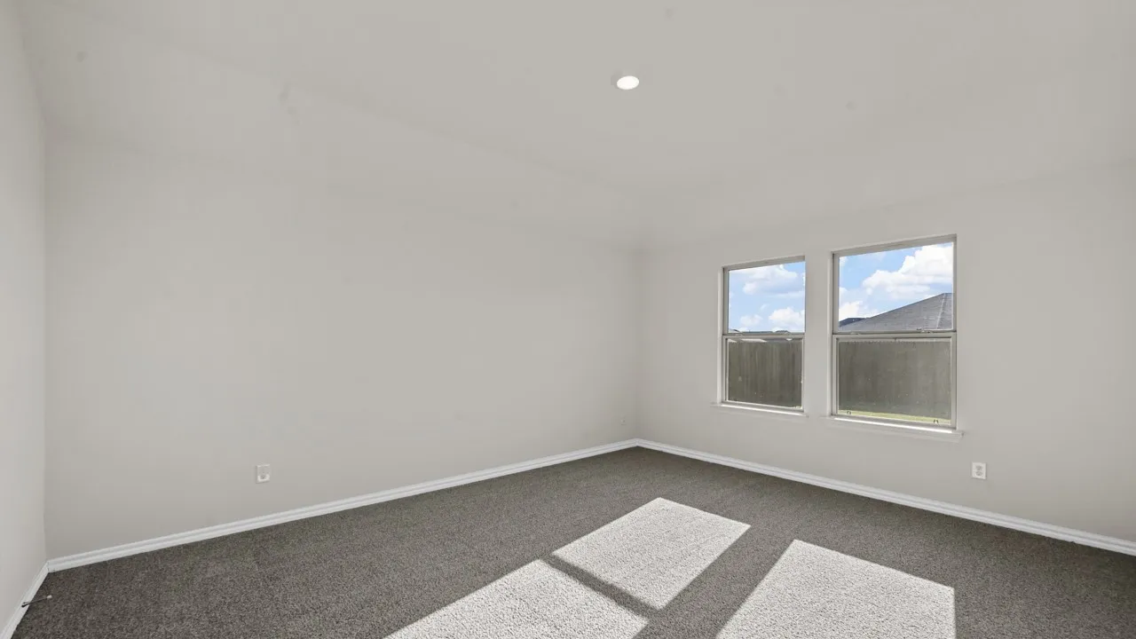 Neutral-toned room featuring a single recessed light fixture, two windows, gray carpet, and white baseboards