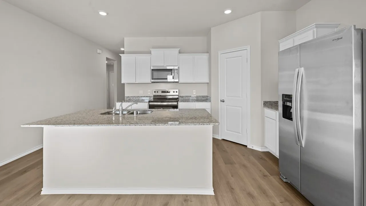 Bright kitchen featuring a central island with a double sink, stainless steel appliances, light wood-finish flooring, white cabinetry, and granite countertops