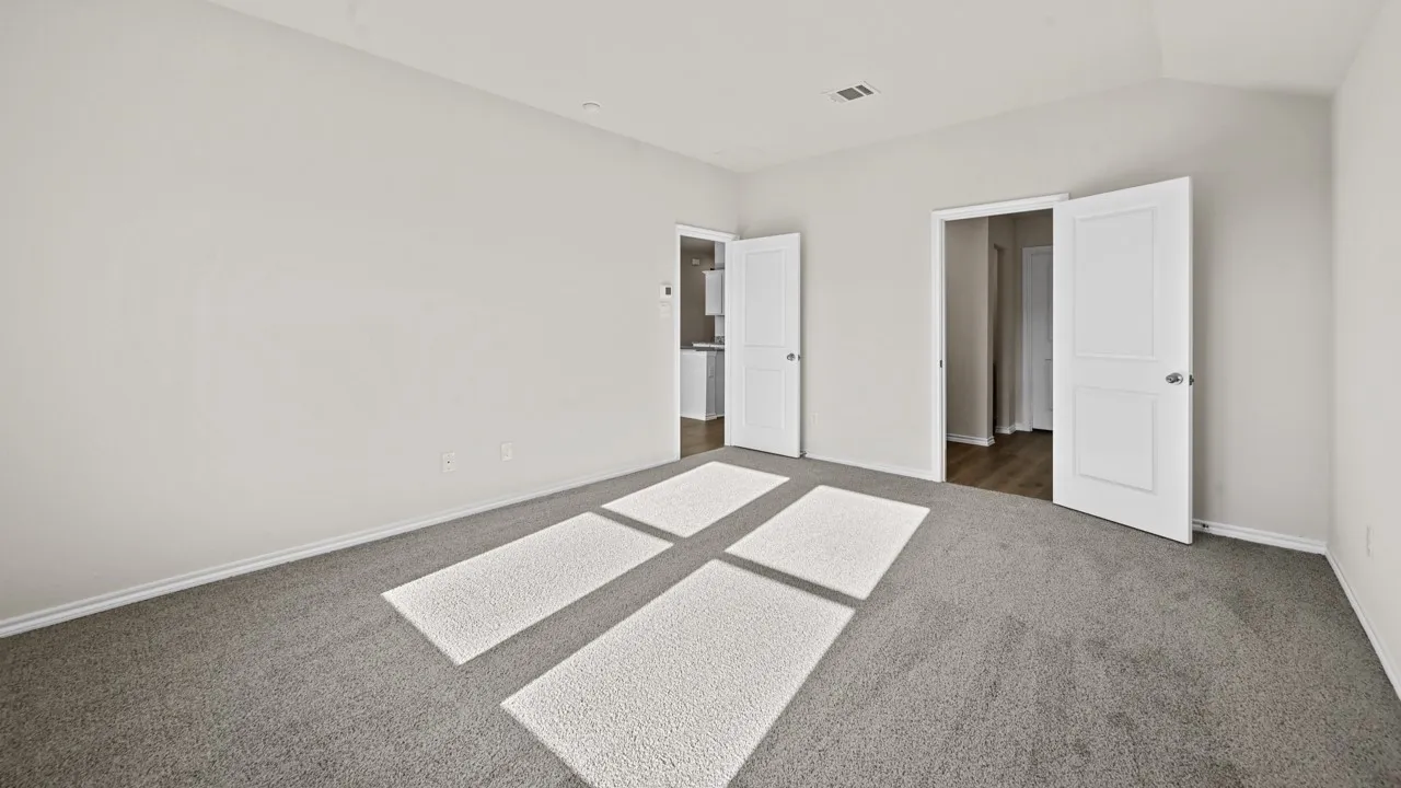 Spacious room featuring neutral-toned walls, textured gray carpeting, white trim, and two panel doors