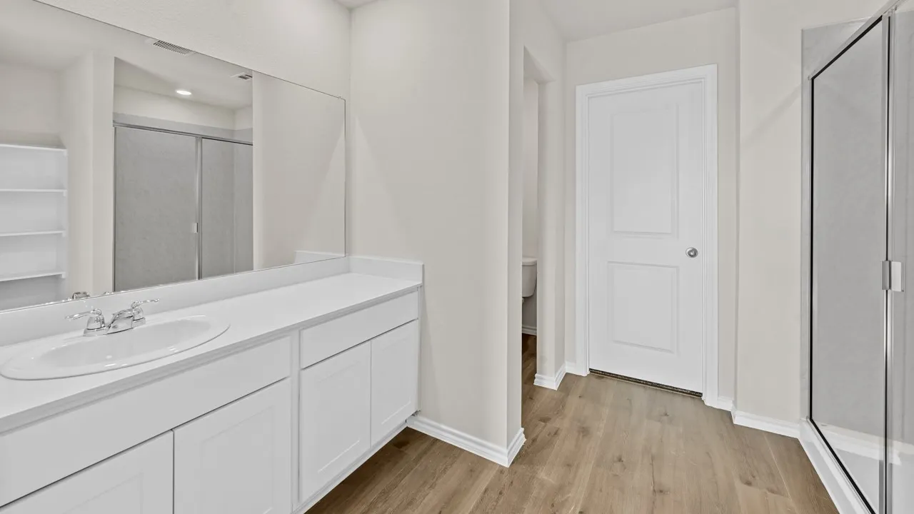 Bathroom featuring a long vanity with an integrated sink, white cabinetry, and a large wall-mounted mirror