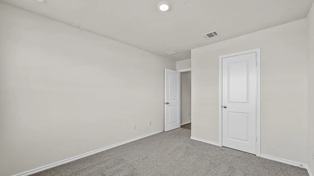 Neutral-toned room featuring a single overhead light fixture, light gray carpeting, white baseboards, and two white panel doors with silver hardware