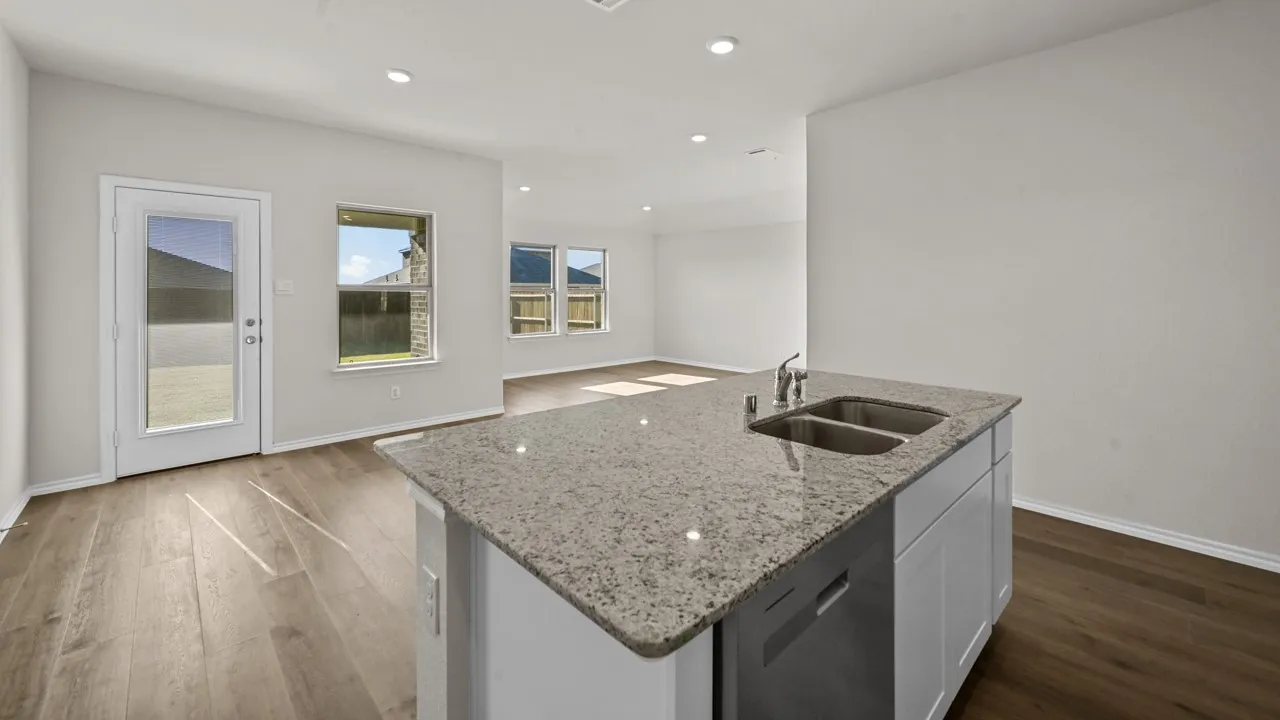 Kitchen island with stone countertop, integrated double basin sink, and stainless steel dishwasher