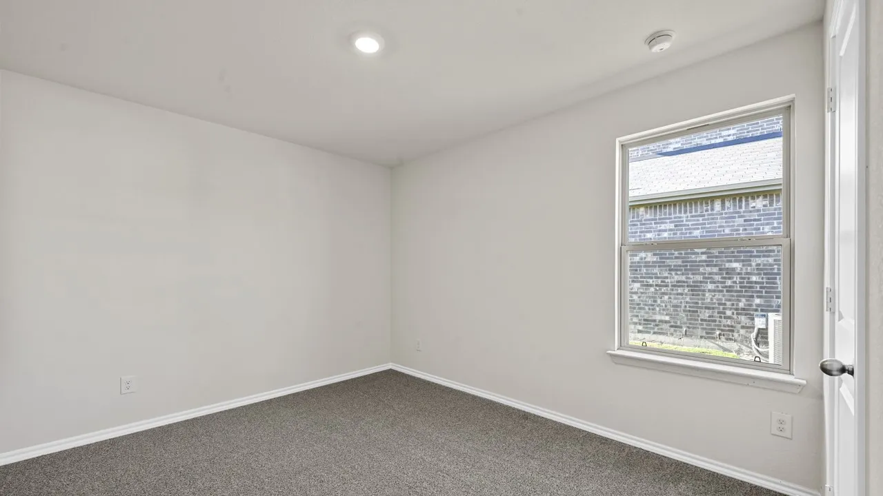 Carpeted room with a single window and recessed ceiling lighting