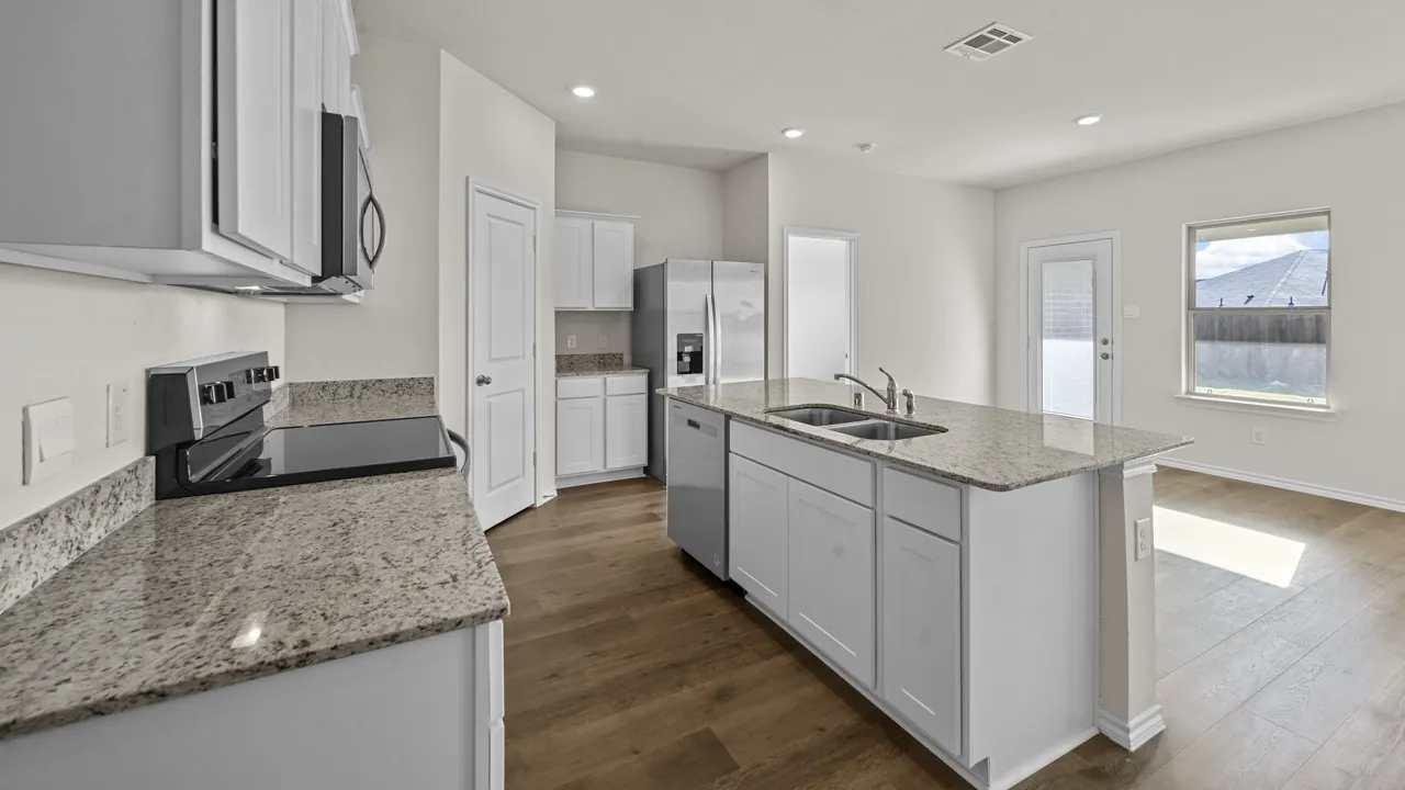 Modern kitchen featuring a central island with dual sinks, granite countertops, white cabinetry, wood-finish flooring, and stainless steel appliances