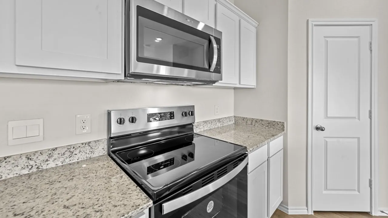 Kitchen with white cabinetry, light-toned speckled countertops, and stainless steel appliances including an oven range and an over-the-range microwave