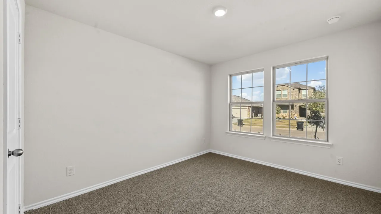 Carpeted room featuring two large windows with grid patterns, white trim, and a neutral wall color