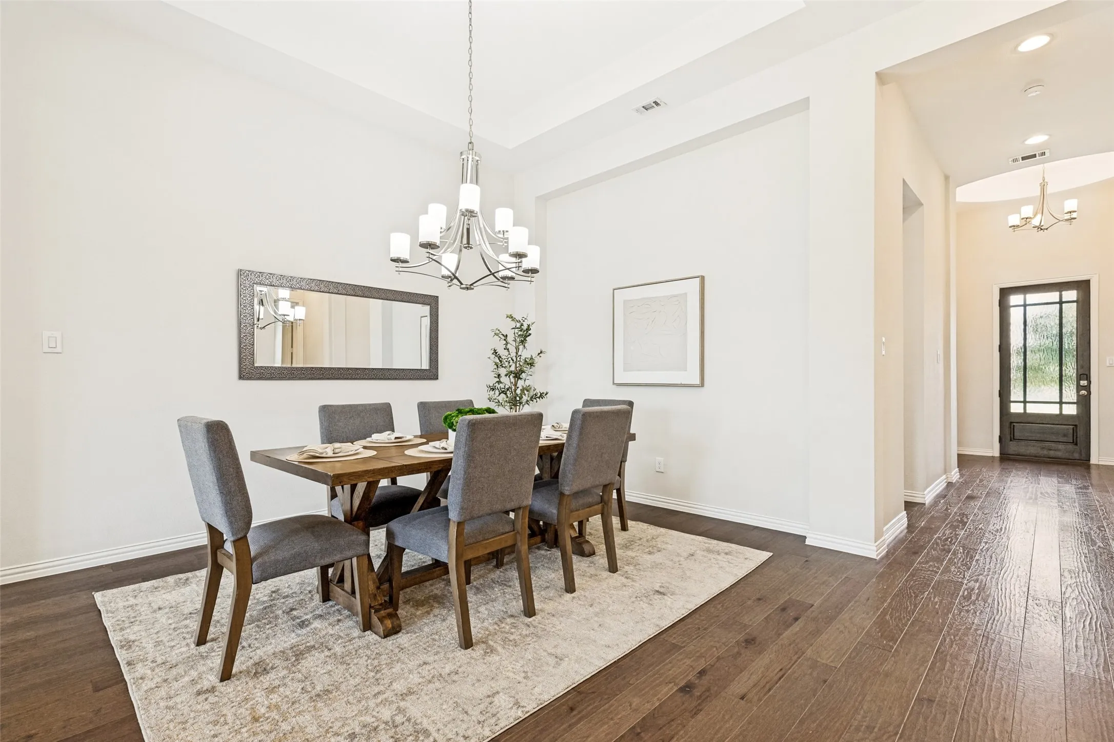 Formal dining space featuring wood-finish flooring, a contemporary chandelier, and high ceilings
