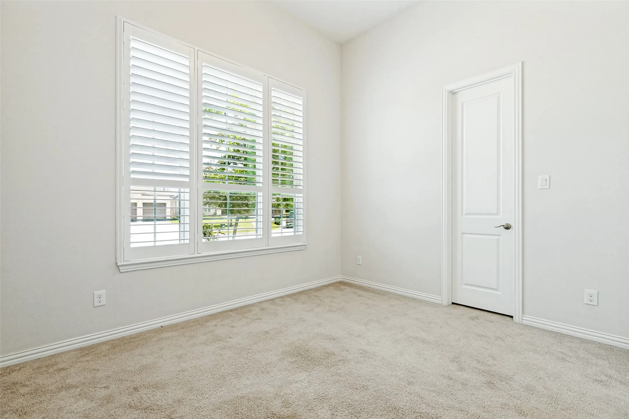 Bright interior space featuring a multi-pane window with white plantation shutters