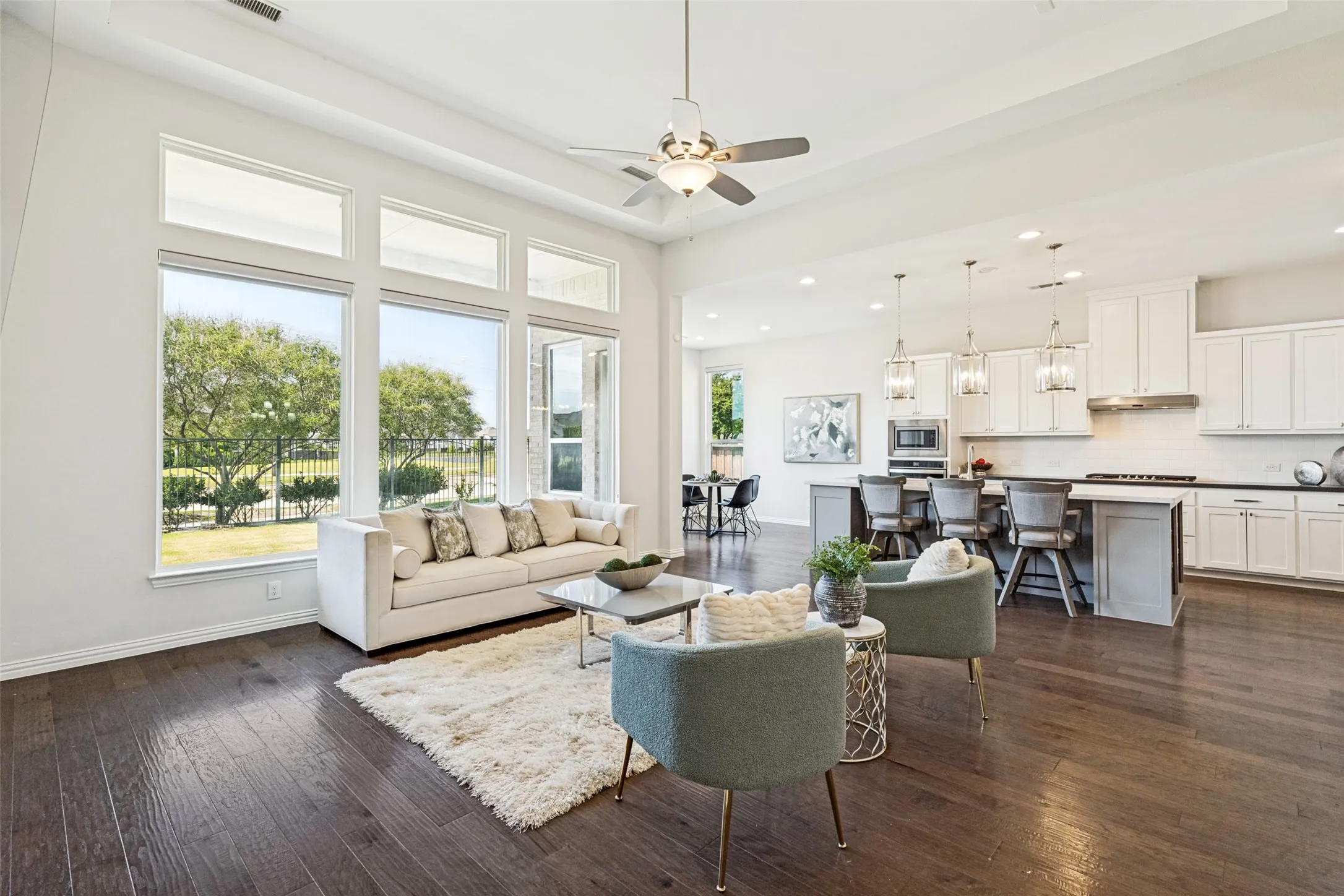 Spacious living area featuring high ceilings, wood-finish flooring, and large windows