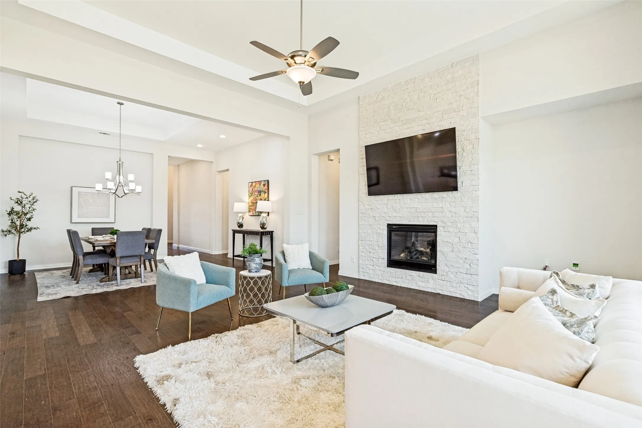 Open-concept living space featuring wood-finish flooring and tray ceilings