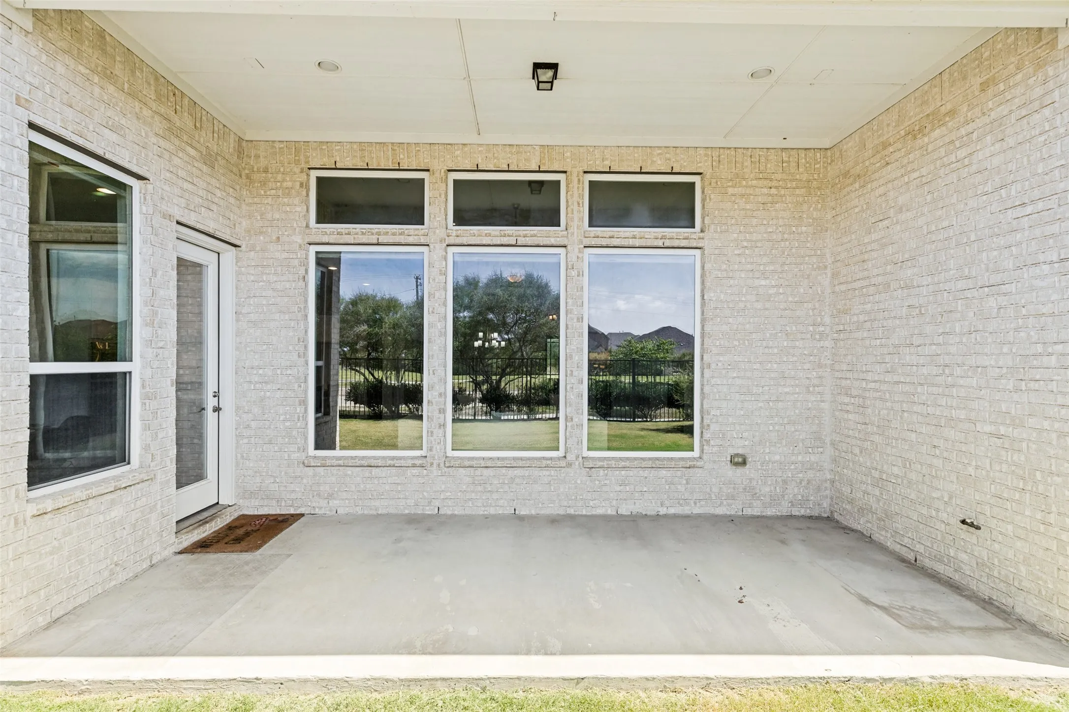 Covered patio featuring a concrete slab and light-colored brick exterior