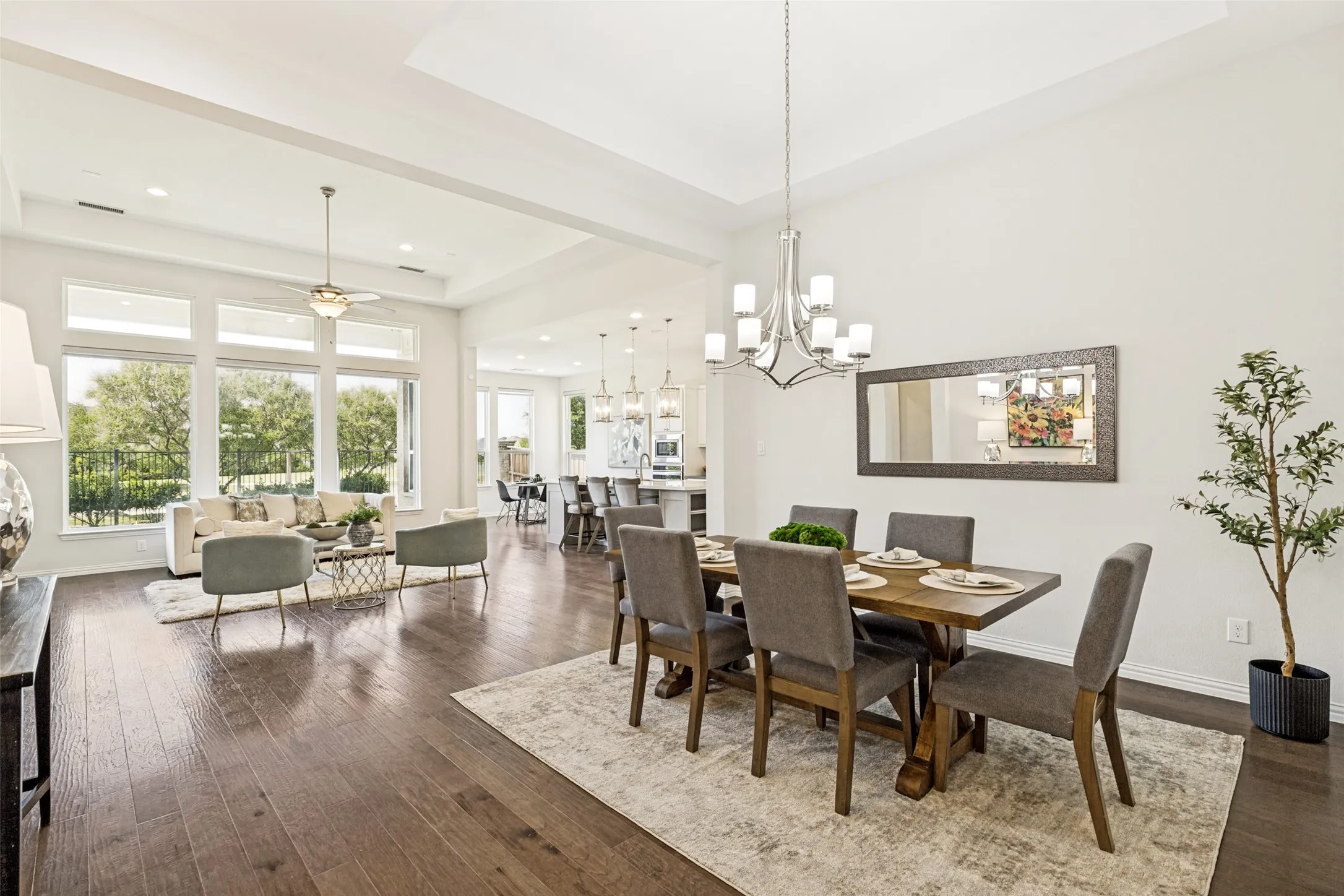 Open-concept living space featuring high ceilings, wood-finish flooring, a contemporary dining chandelier, and recessed lighting