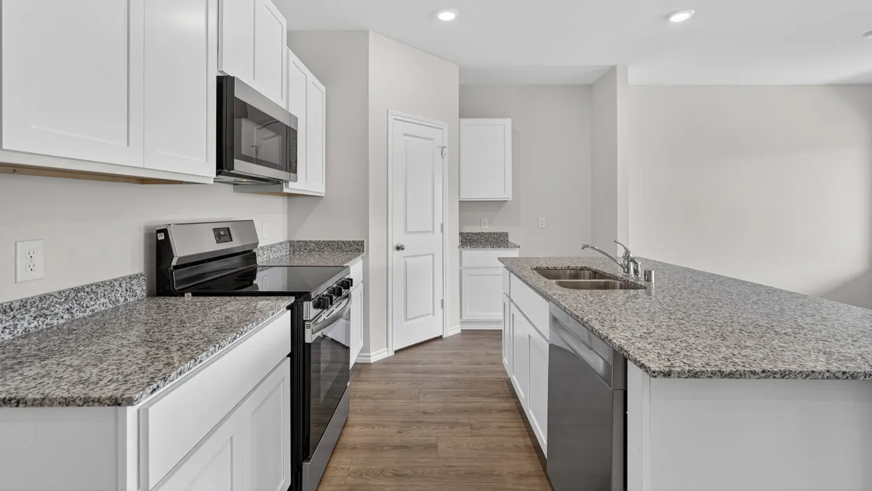 Modern kitchen featuring white cabinetry, speckled countertops, stainless steel appliances, and wood-finish flooring