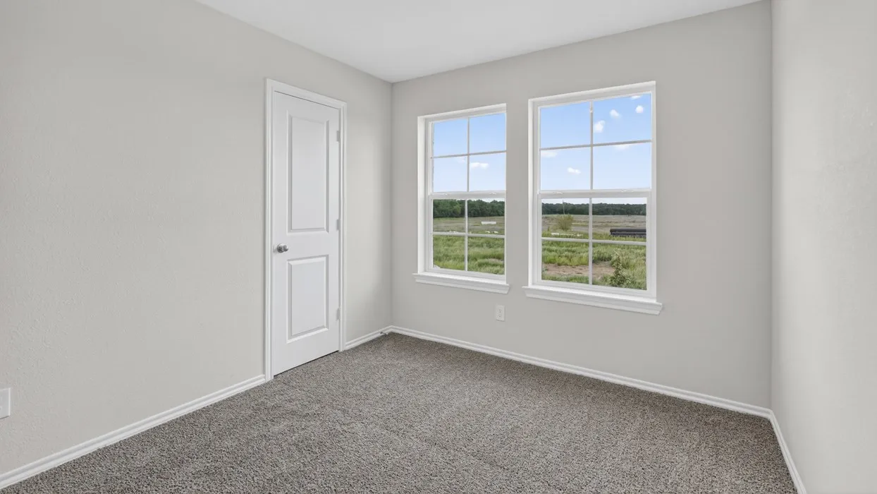Room featuring two windows with white frames, providing natural light and a field scenery