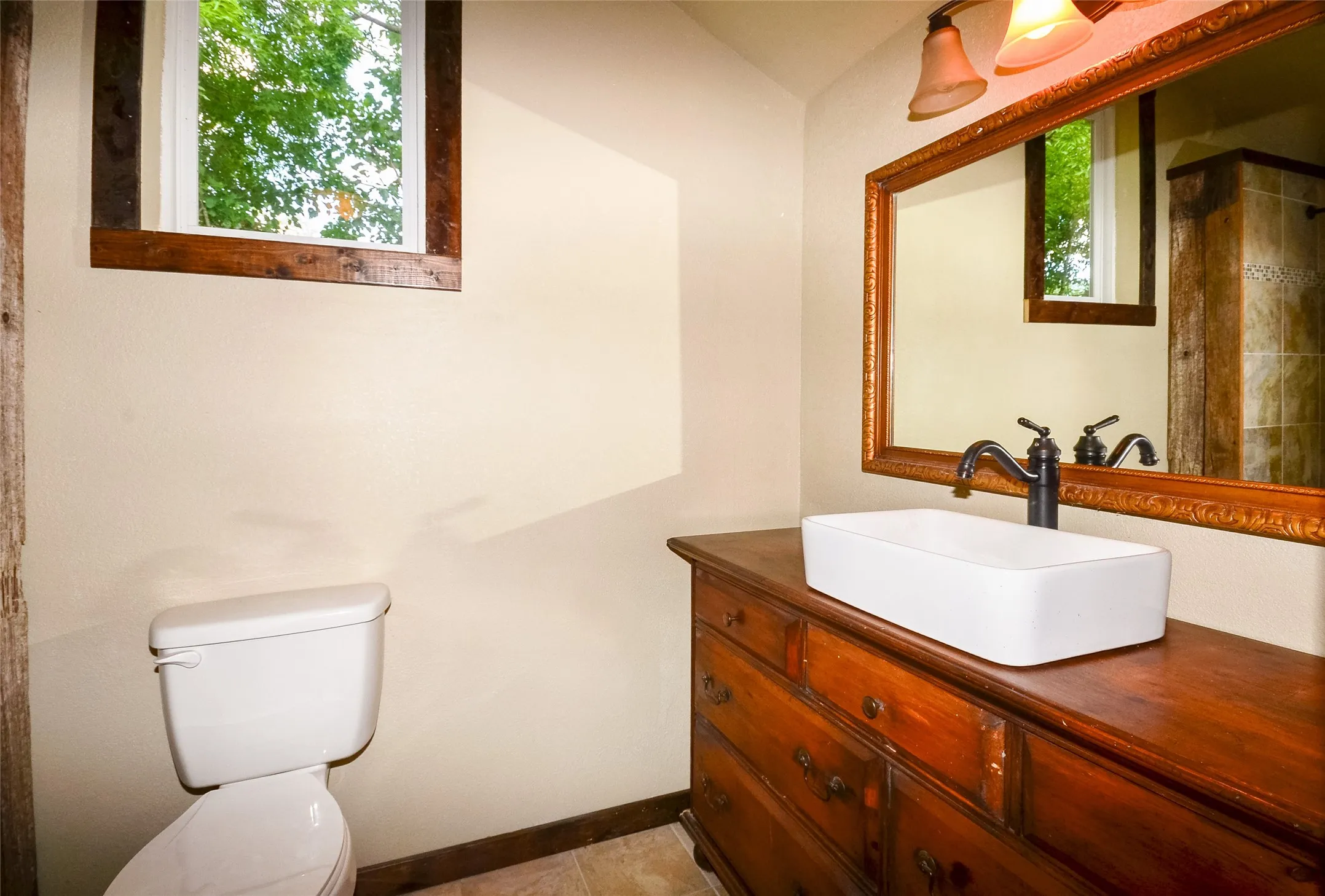 Bathroom vanity featuring a rectangular vessel sink, oil-rubbed bronze faucet, and a large framed mirror