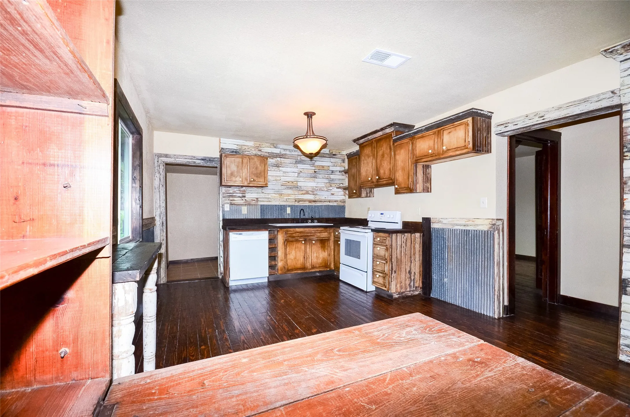 Kitchen featuring dark wood-finish flooring, wood cabinetry, a stone accent wall, and built-in appliances