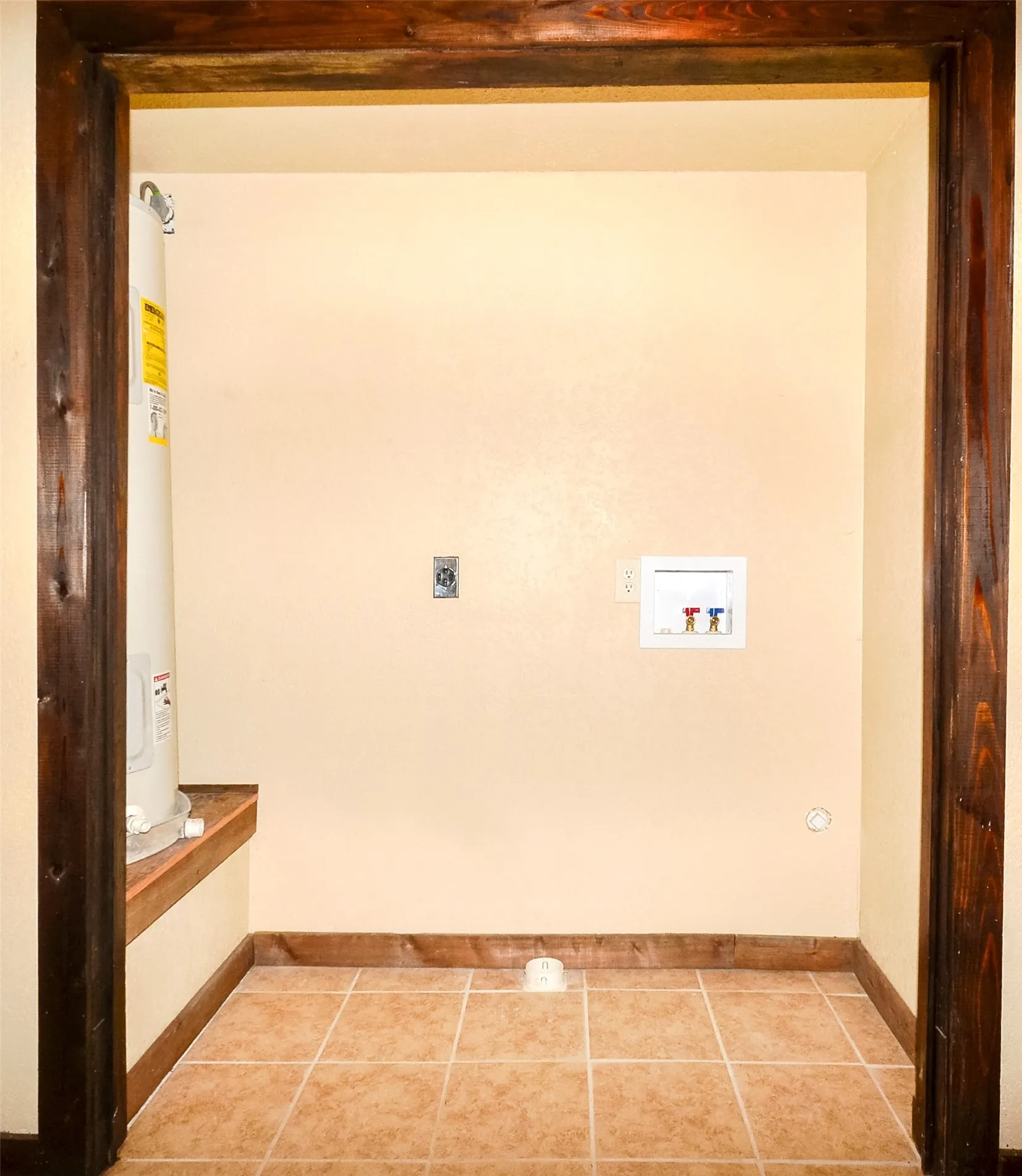 Utility space featuring warm-toned ceramic tile flooring and light cream walls
