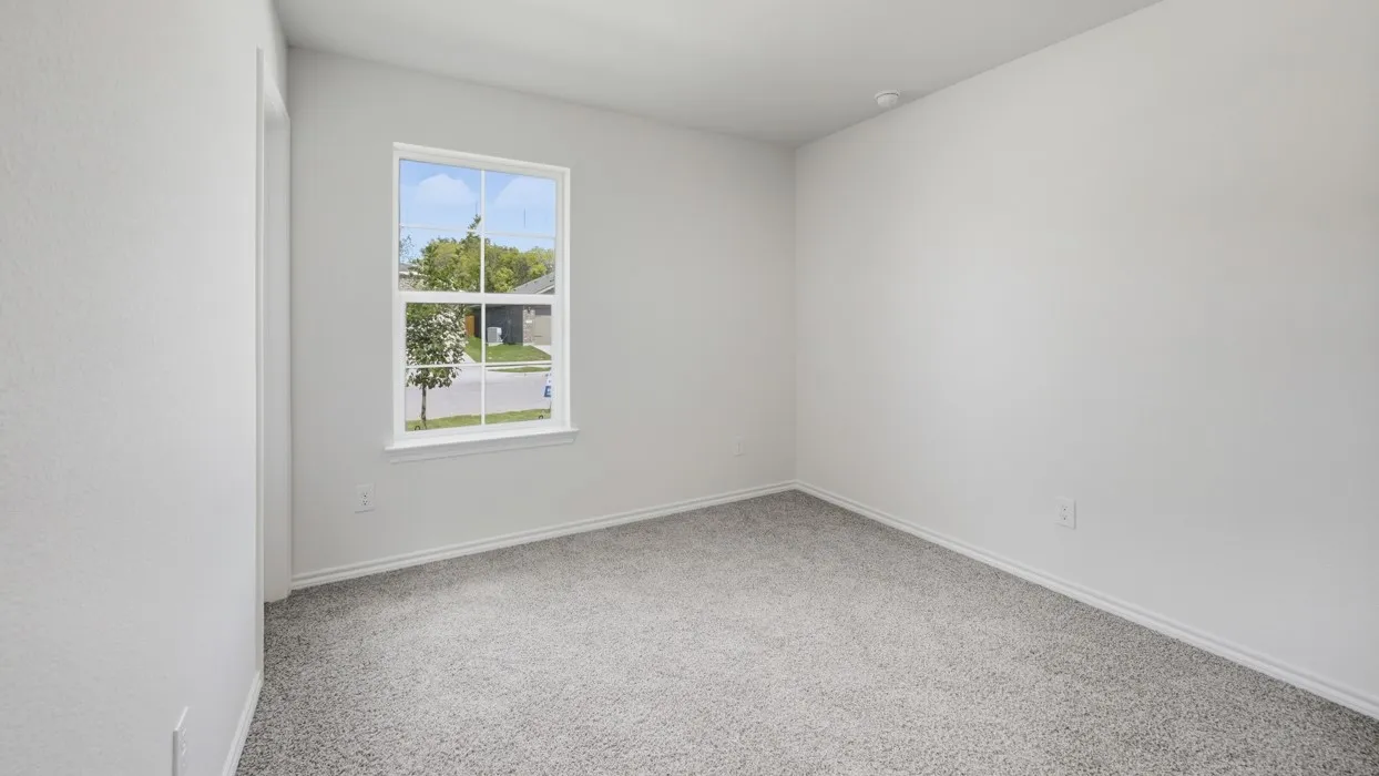 Room featuring light gray textured carpeting, white walls, and a white-trimmed window with grid panes