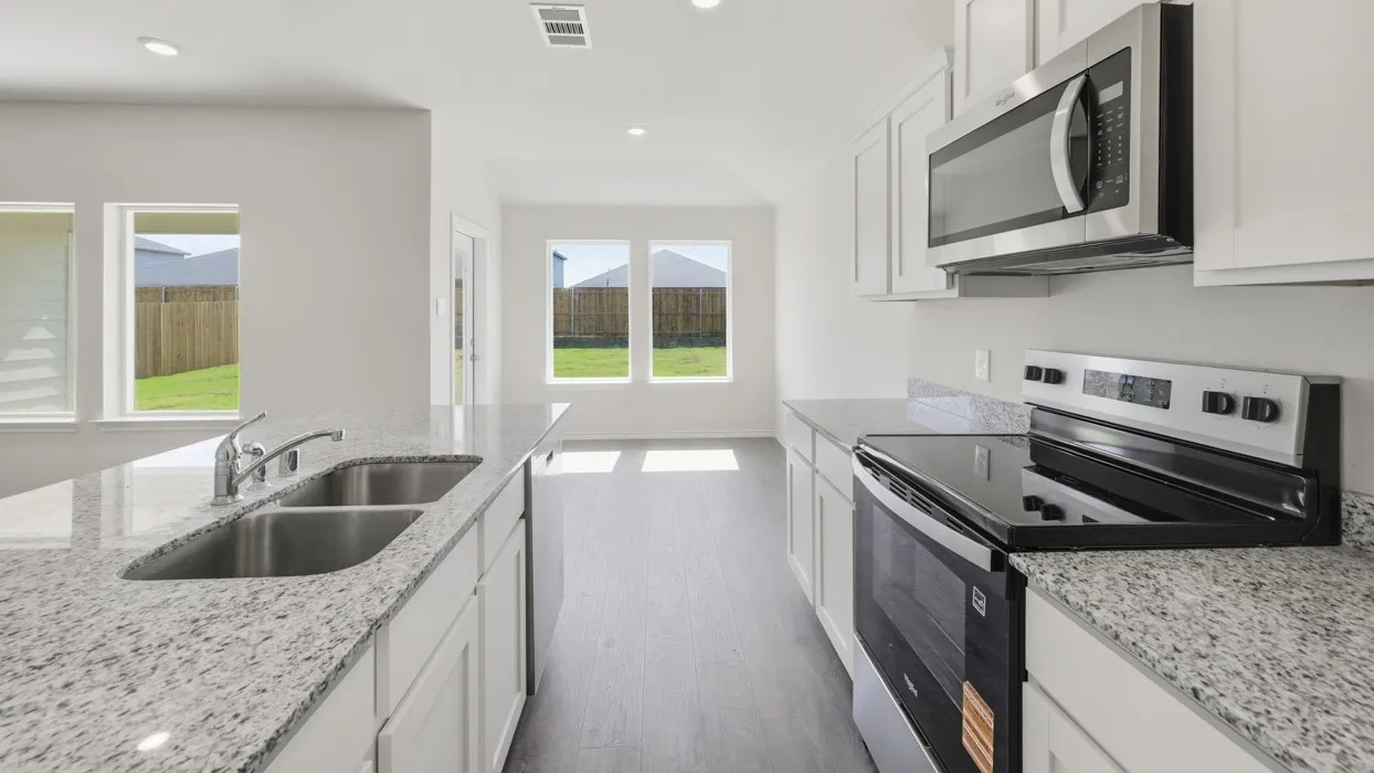 Open-concept kitchen featuring granite countertops, a double basin stainless steel sink, wood-finish flooring, white cabinetry, and stainless steel appliances