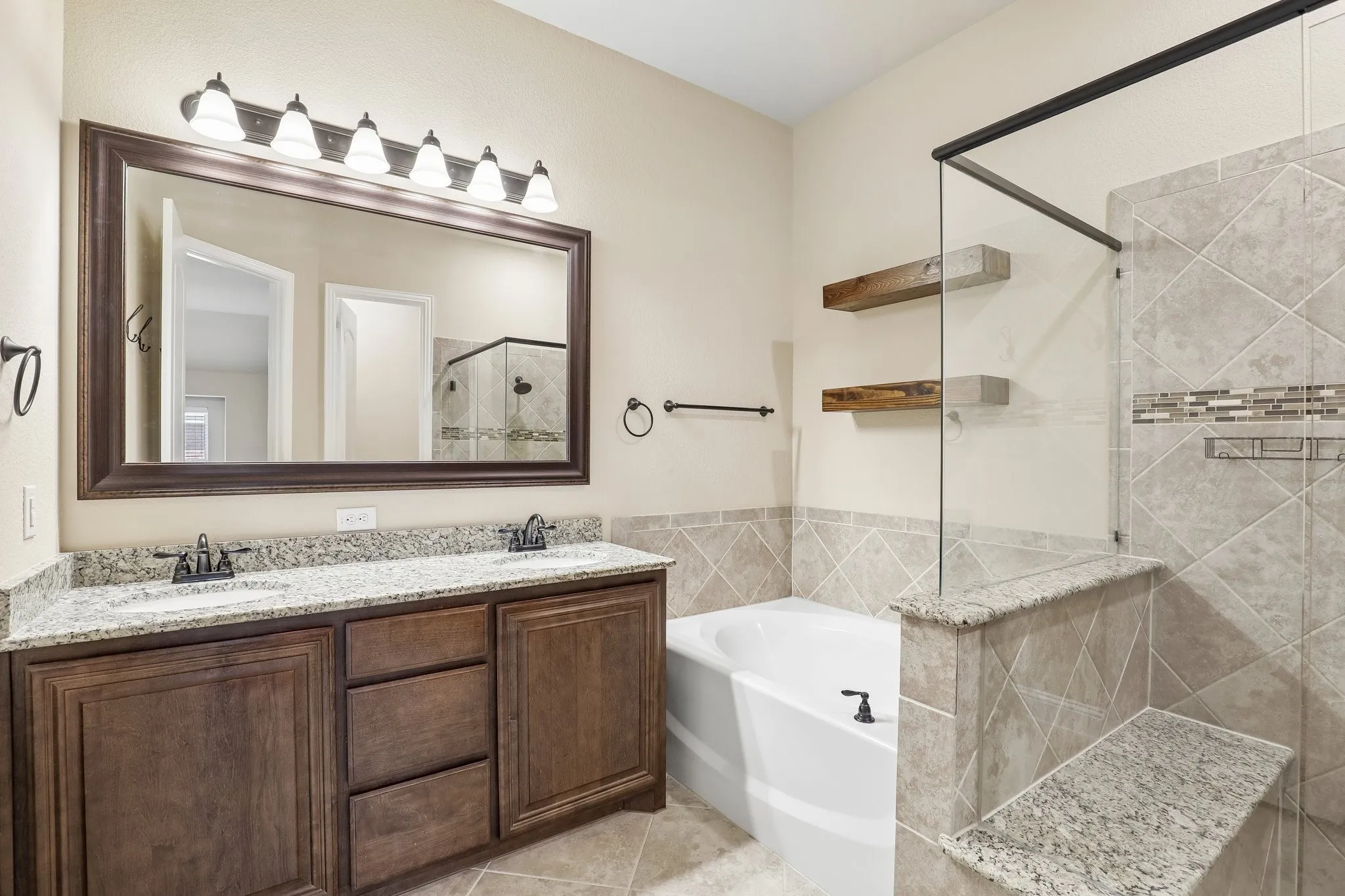 Bathroom featuring a double vanity with granite countertops, wood-finish cabinetry, and framed mirror with six-light fixture
