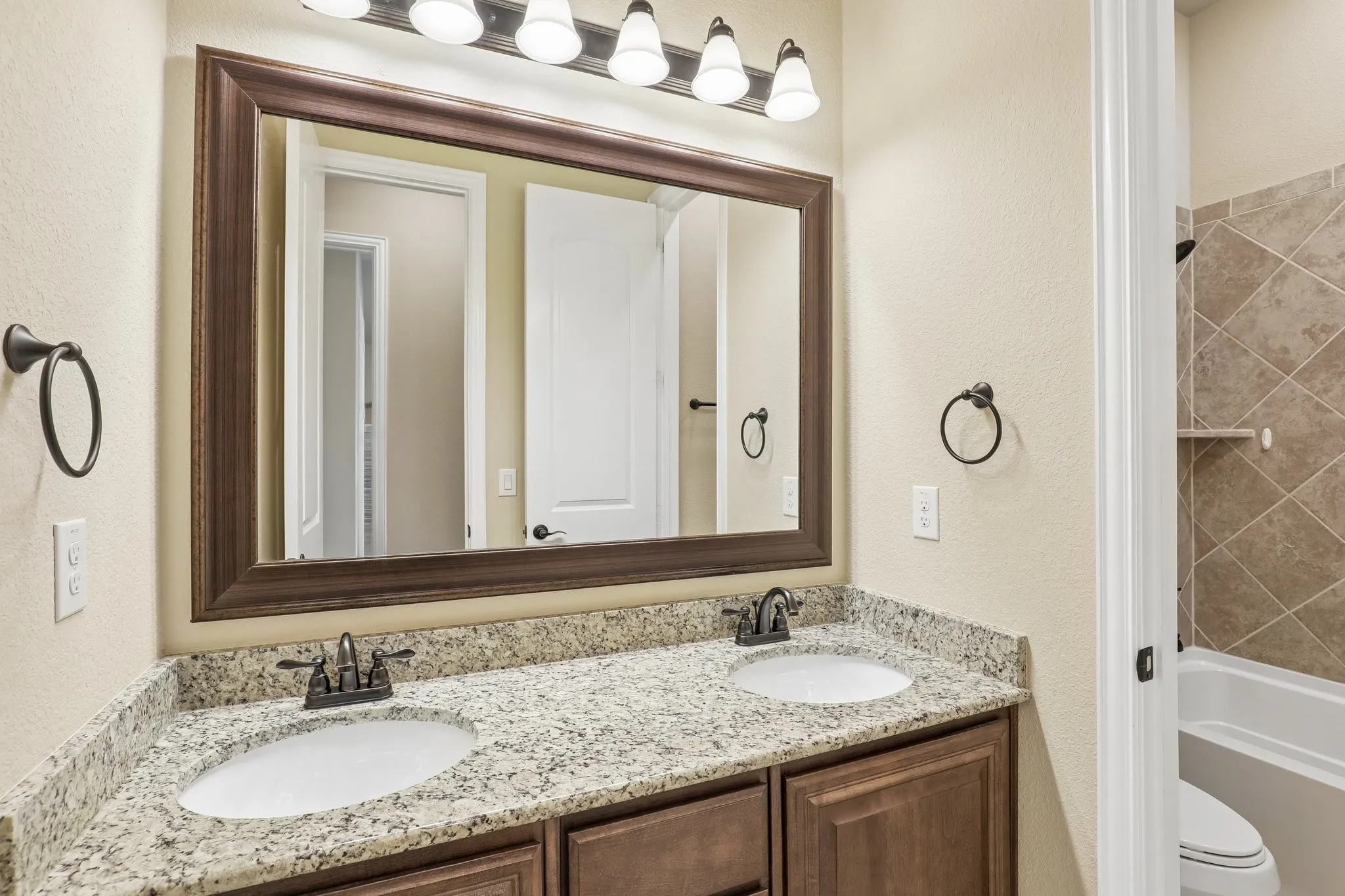 Dual vanity with speckled countertop and dark wood cabinetry