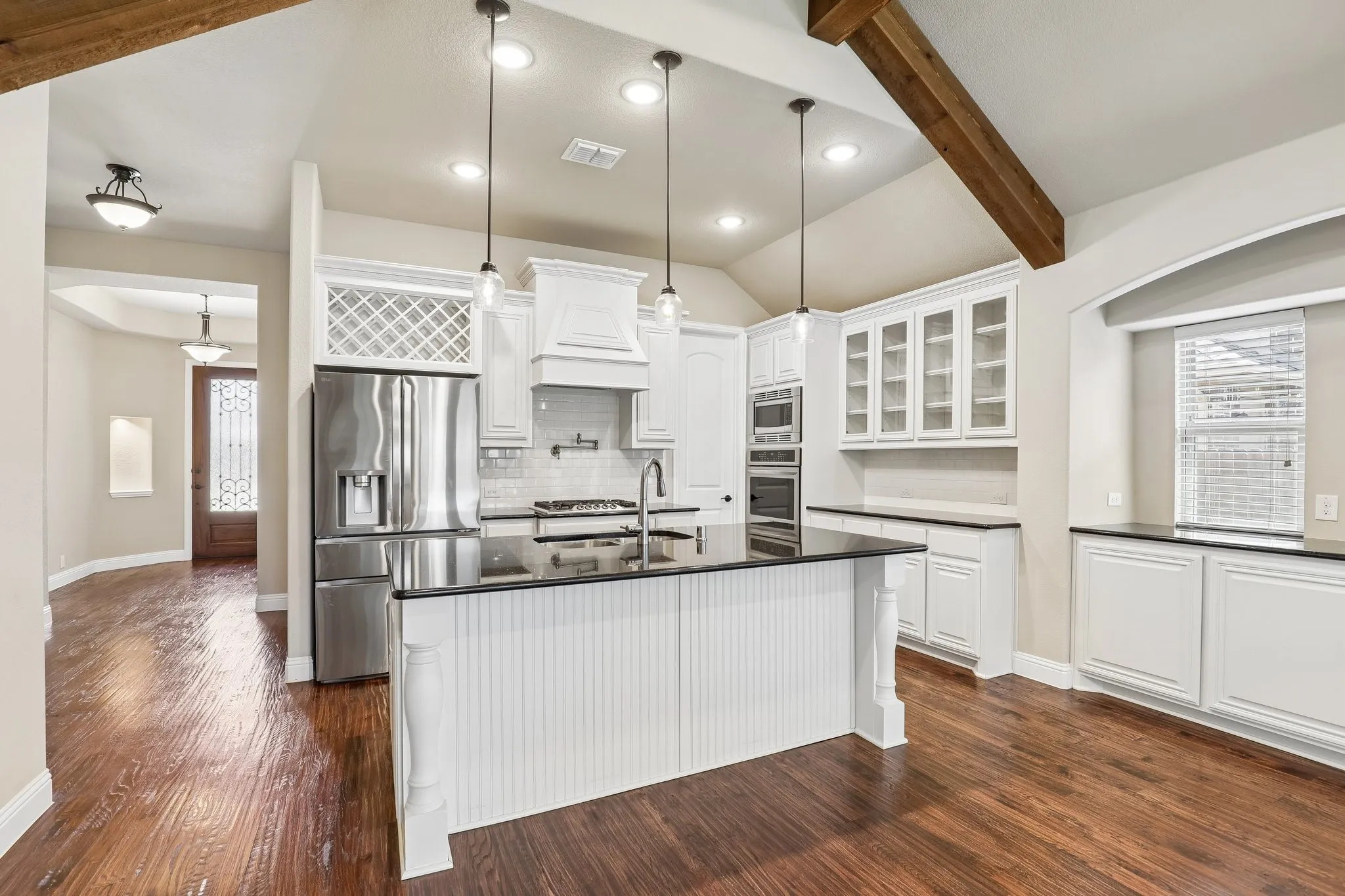 Gourmet kitchen with a central island, stainless steel appliances, white cabinetry, and dark countertops