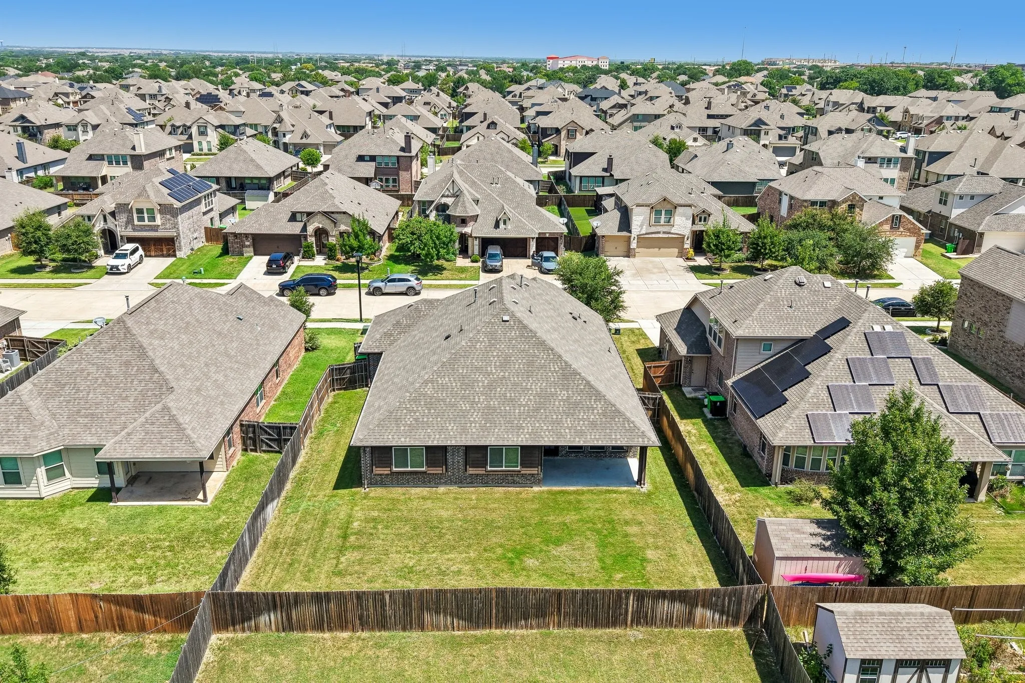 Expansive backyard featuring a manicured lawn, a full wooden privacy fence, and a covered patio area