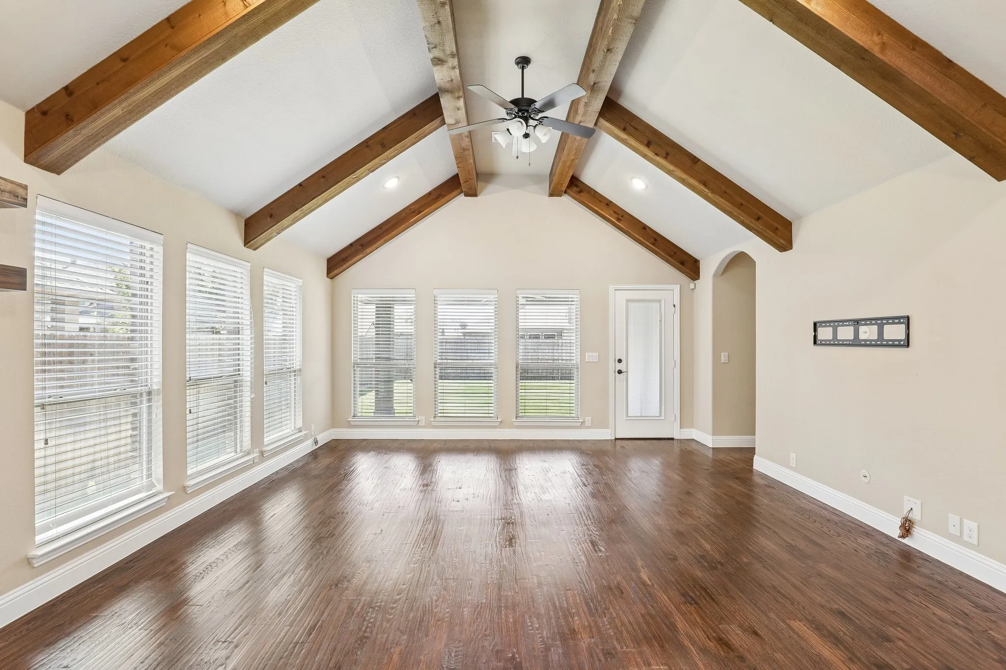 Spacious room featuring a vaulted ceiling with exposed wood beams, recessed lighting, and a ceiling fan
