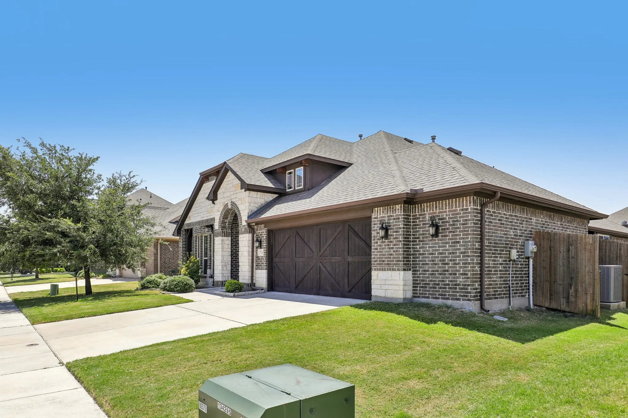 Brick and stone exterior featuring an arched entryway, gabled roofline, and dormer window
