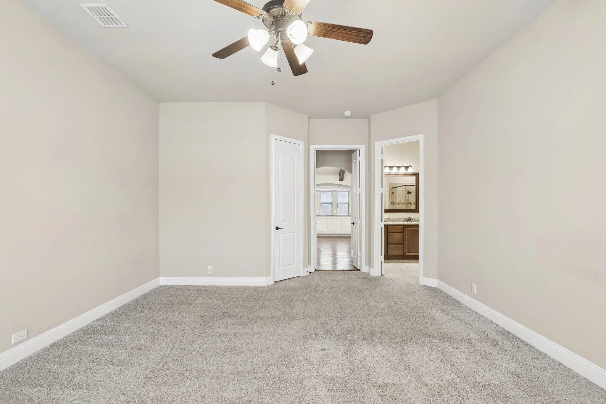 Spacious room featuring light gray carpeting, neutral wall paint, white trim, a ceiling fan with integrated lighting, and two panel doors