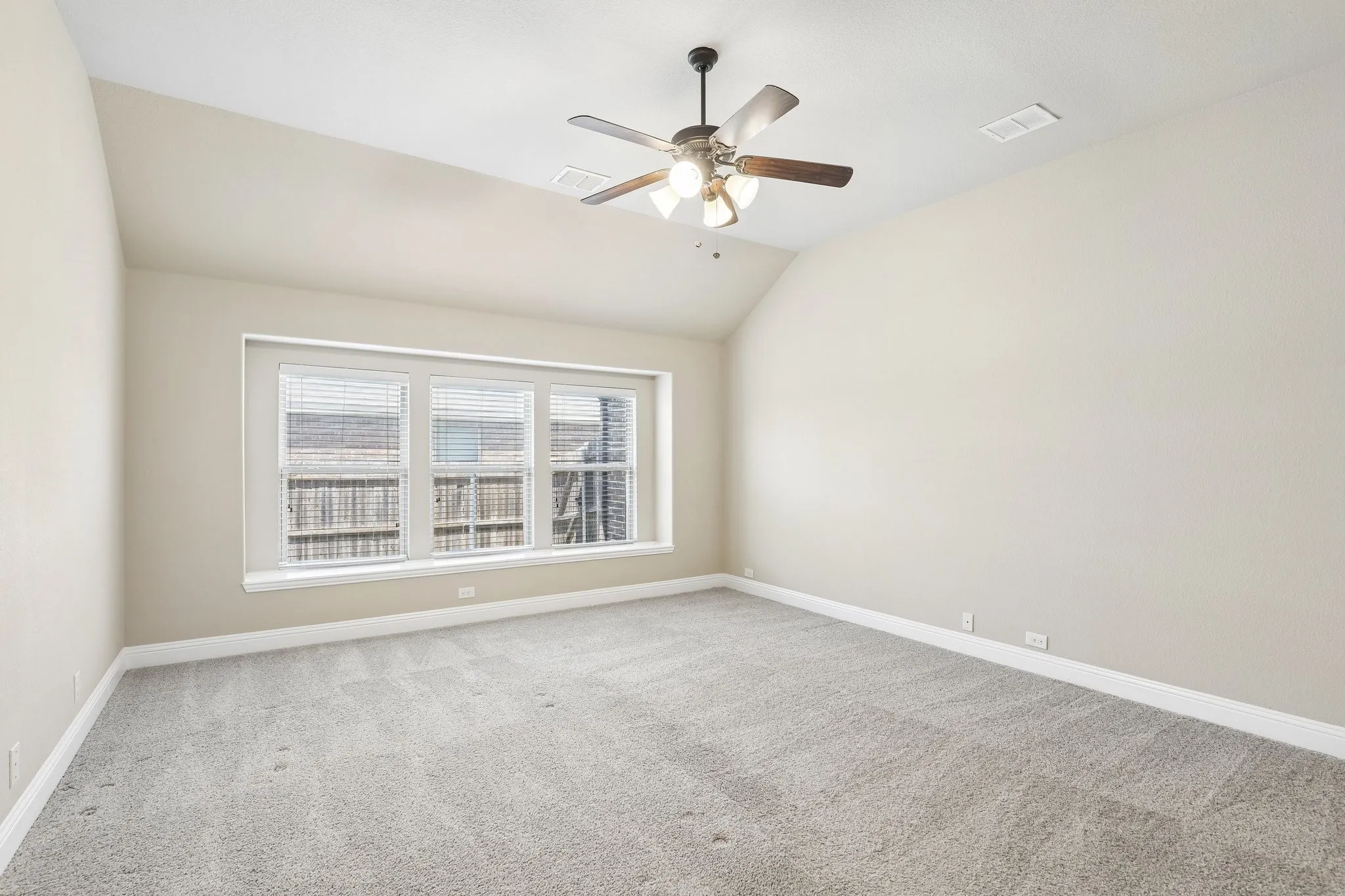 Spacious room featuring vaulted ceilings, light-toned walls, and plush carpeting