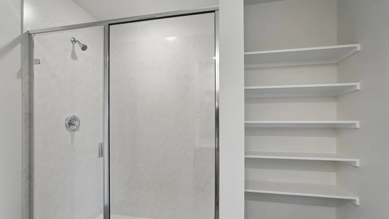 Shower enclosure with chrome fixtures and integrated shelving